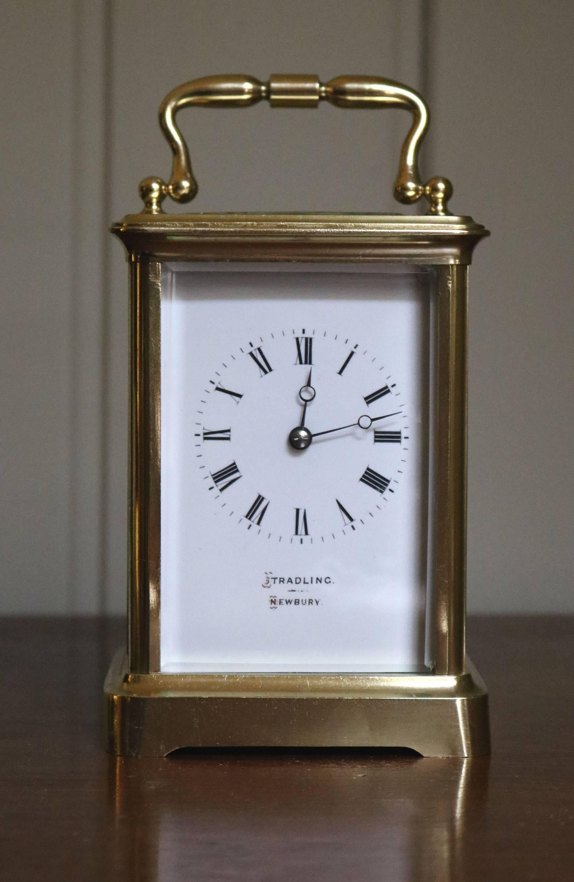 A high quality large timepiece carriage clock. The corniche case has a large oval top window and bevel glass sides. Its enamel dial has fine moon hands and the dial is signed by the original retailers, stradling of Newbury. It has an 8 day movement