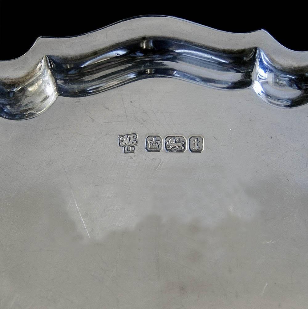 A Geo. V sterling silver "Chippendale" border card tray supported by three hoof feet. No inscription.