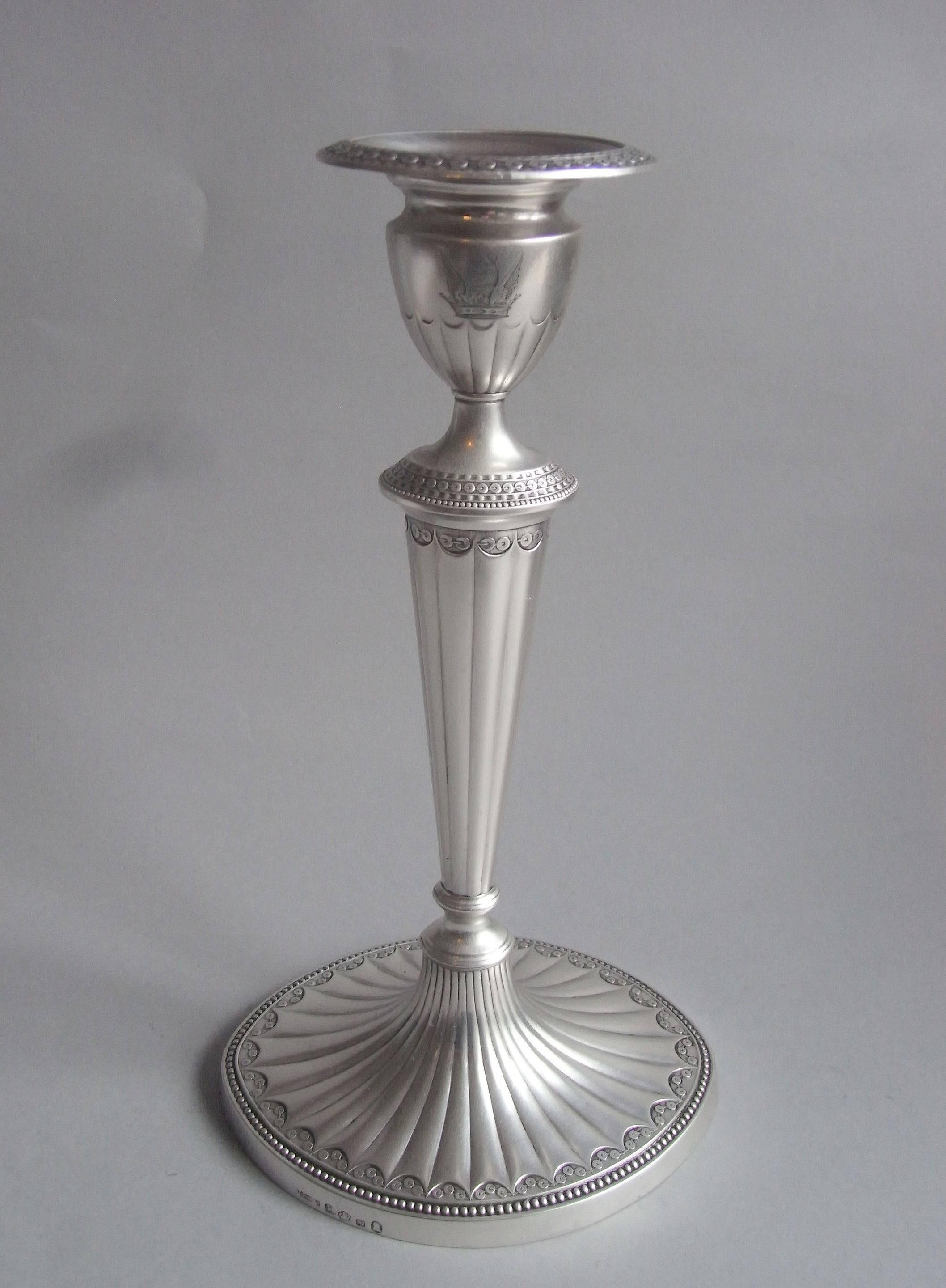 The Candlesticks unusually display oval bases which are decorated with bat wing fluting and beading as well as tiny stylized roundels which are threaded together to form a shaped band at the edge of the fluting. The main shaft and socket are also