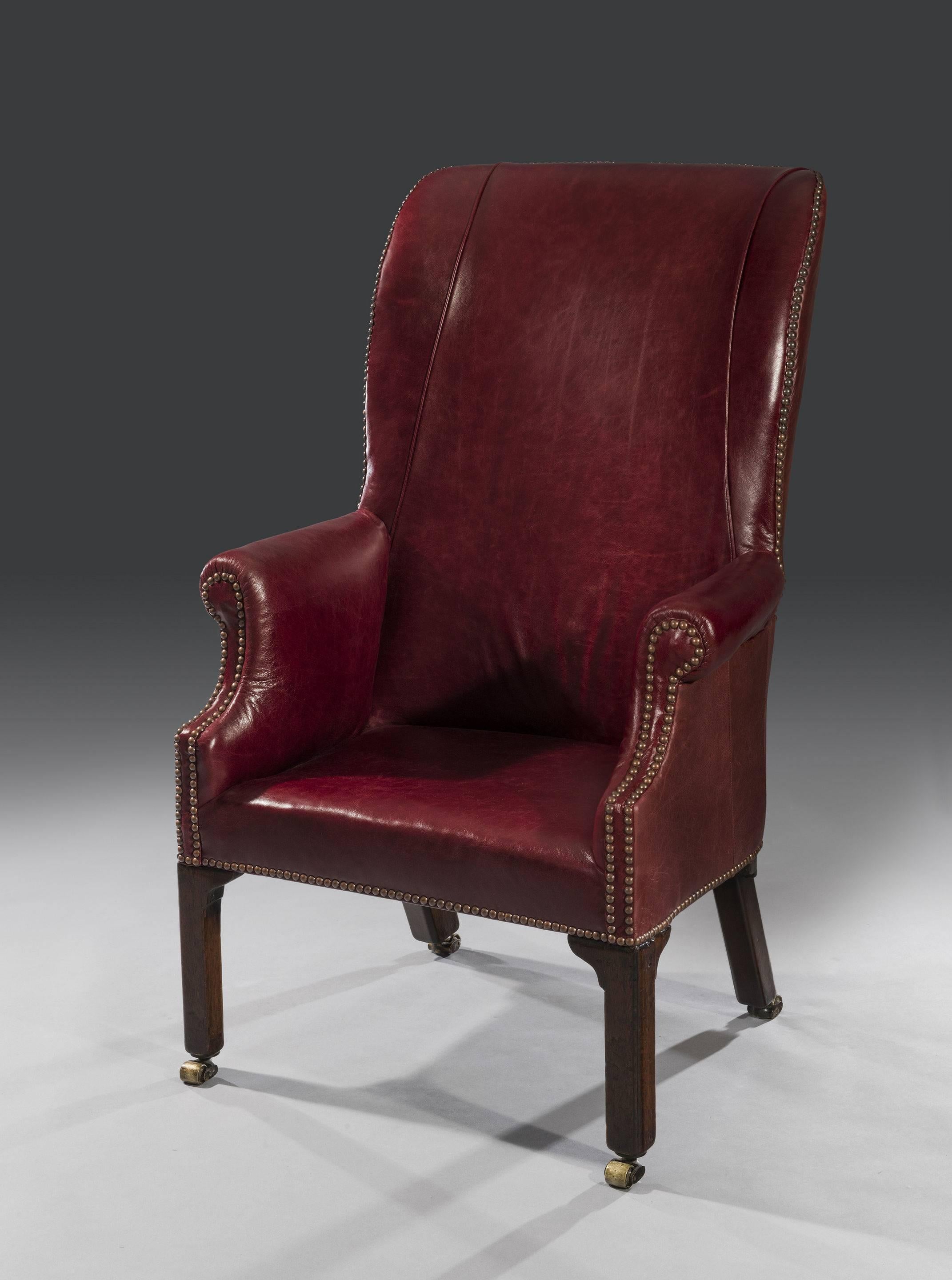 The 'horseshoe-shaped' or 'barrel-shaped' gentleman's armchair has recently been re-upholstered in a red crimson leather and has a fitted seat. The proportions are elegant and petite and the chair stands on solid Cuban mahogany outswept rear legs