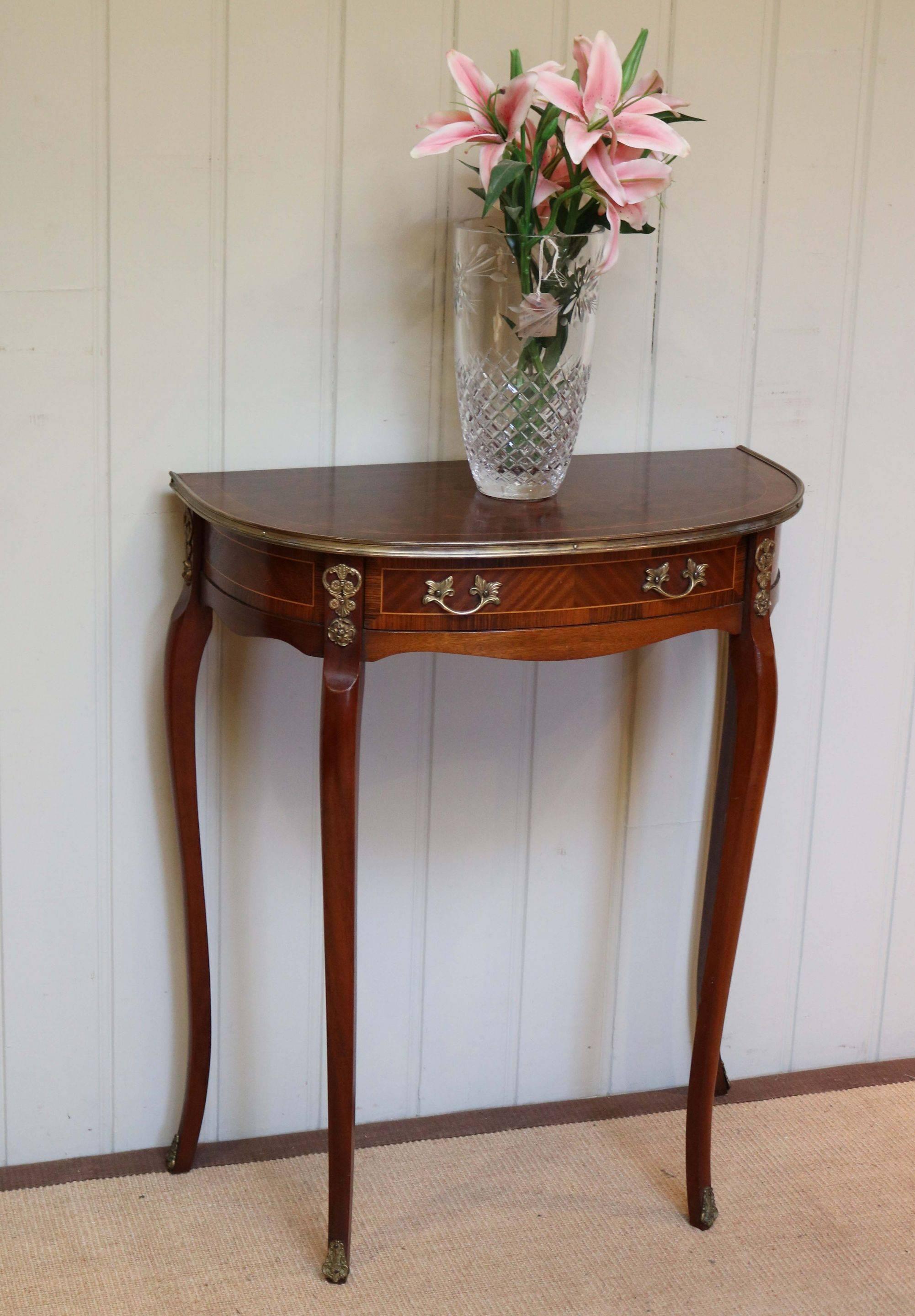 French mahogany demilune table having a parquetry top with brass banding above a single drawer raised on shaped legs with applied brass mouldings.