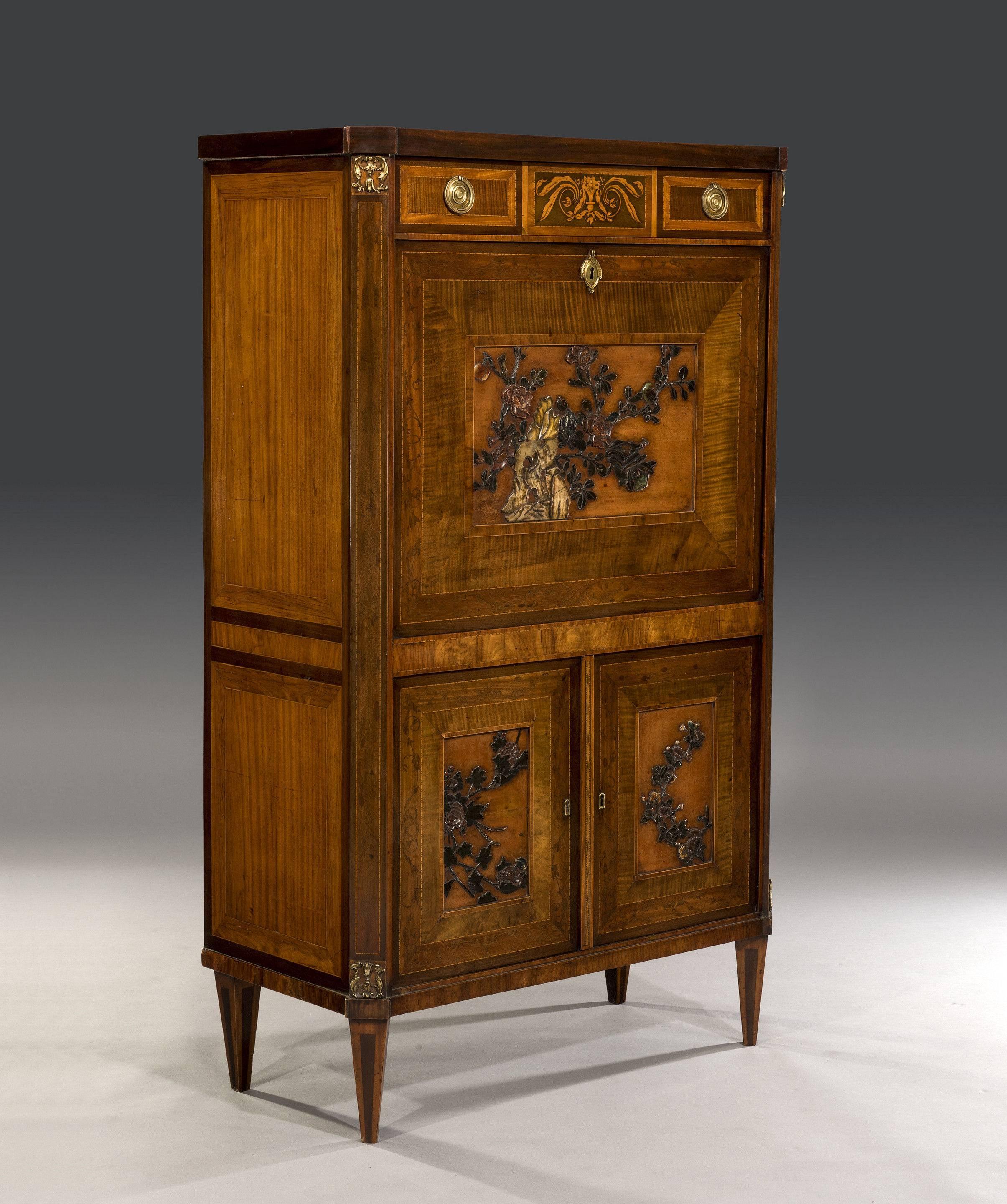 The mahogany top sits above a single drawer that is highly decorated with an inlaid centre panel which is flanked by two cross-banded smaller panels with brass ringed handles. The escritoire's fall is cross-banded and inlaid with floral scrolls and