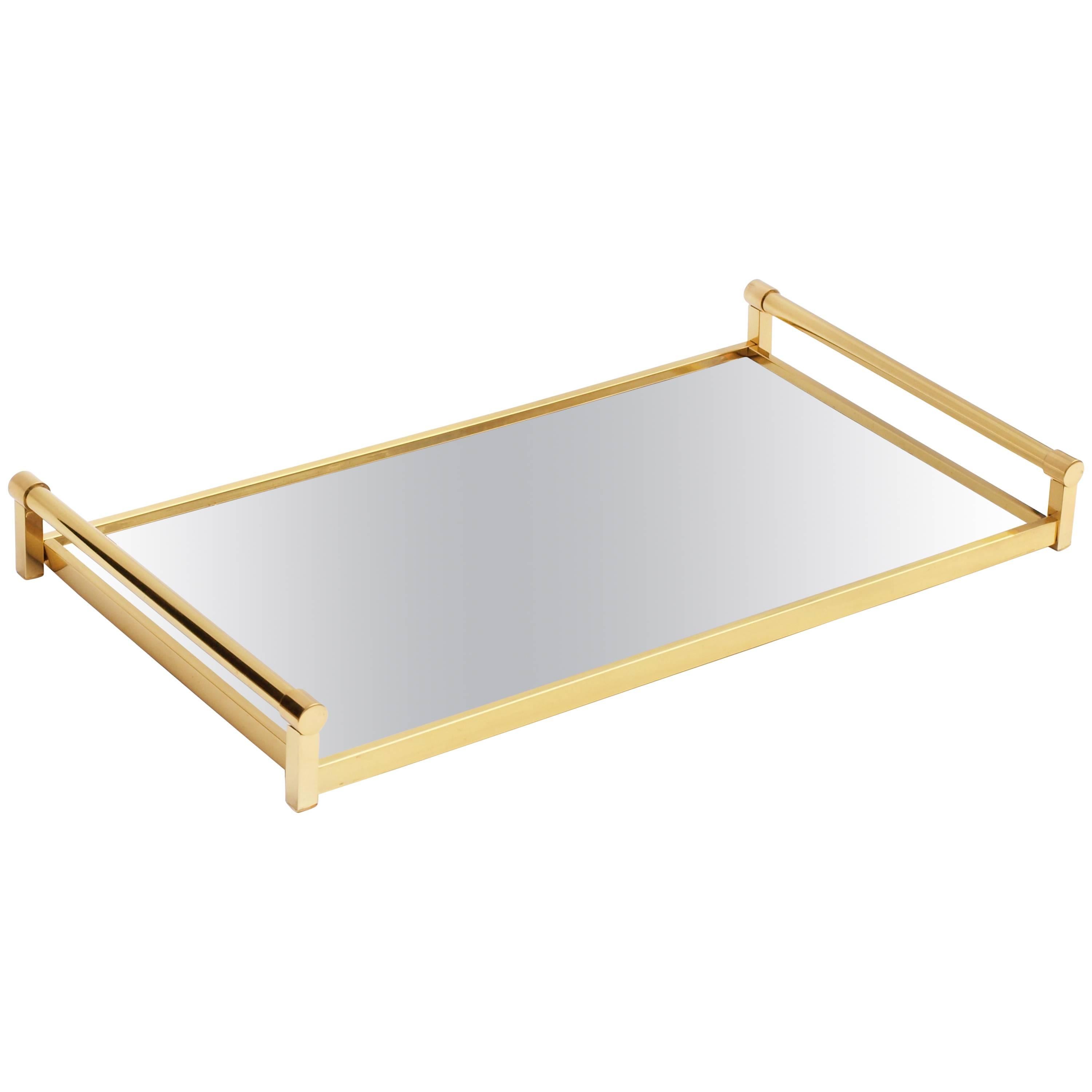 A rare example of this stunning and well documented tray by Jacques Adnet for Compagnie Des Arts Francais , in virtually unused condition. 
Exuding style in its simplicity, the tray is finished in polished brass and mirrored glass base that