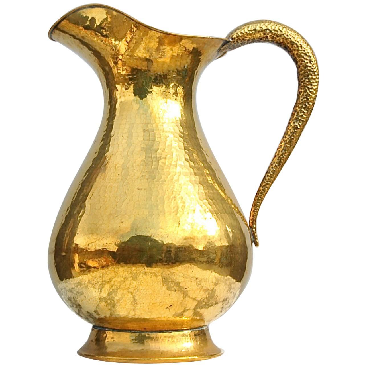 Richly textured handmade oversize vase or umbrella stand in the shape of a jug. The main body is made from a single thick piece or sheet of hammered brass, a work done by hand by an experienced craftsman. The surface of the curved handle has a