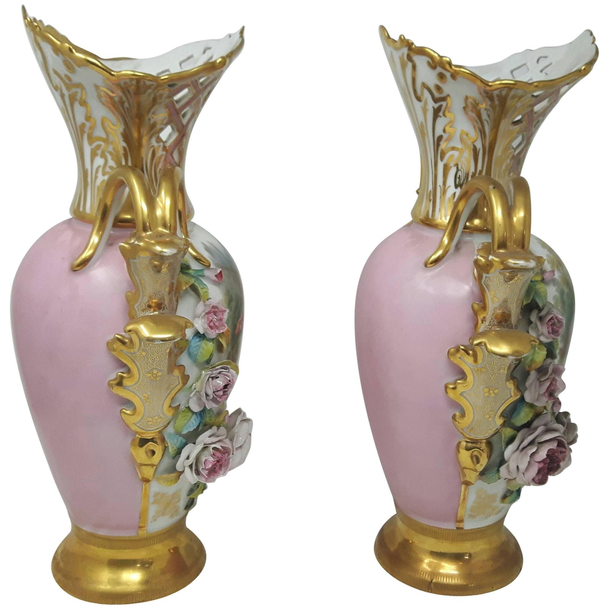 A Regency style pair of Paris porcelain vases with delightful hand-painted panels of pastoral children's scenes, surrounded by encrusted flowers on a gilded base. The latice worked necks are adorned by a large white and gilt leaf, and gilded