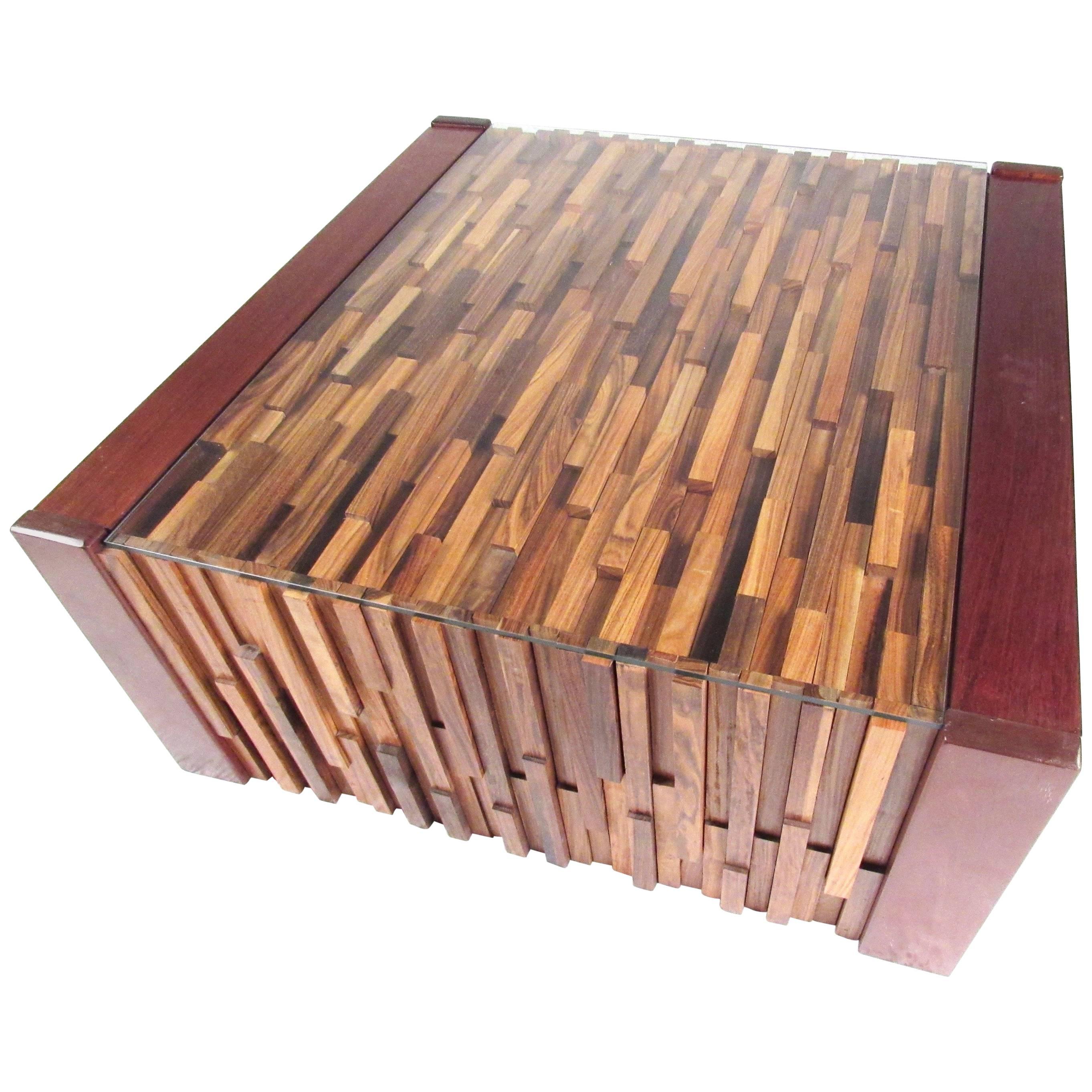Questo imponente tavolino in legno duro brasiliano presenta un piano scolpito in stile brutalista con un mix di legni per un design scultoreo e un piano in vetro protettivo. Questo design di Percival Lafer, in Brasile, è un tavolino da salotto o un