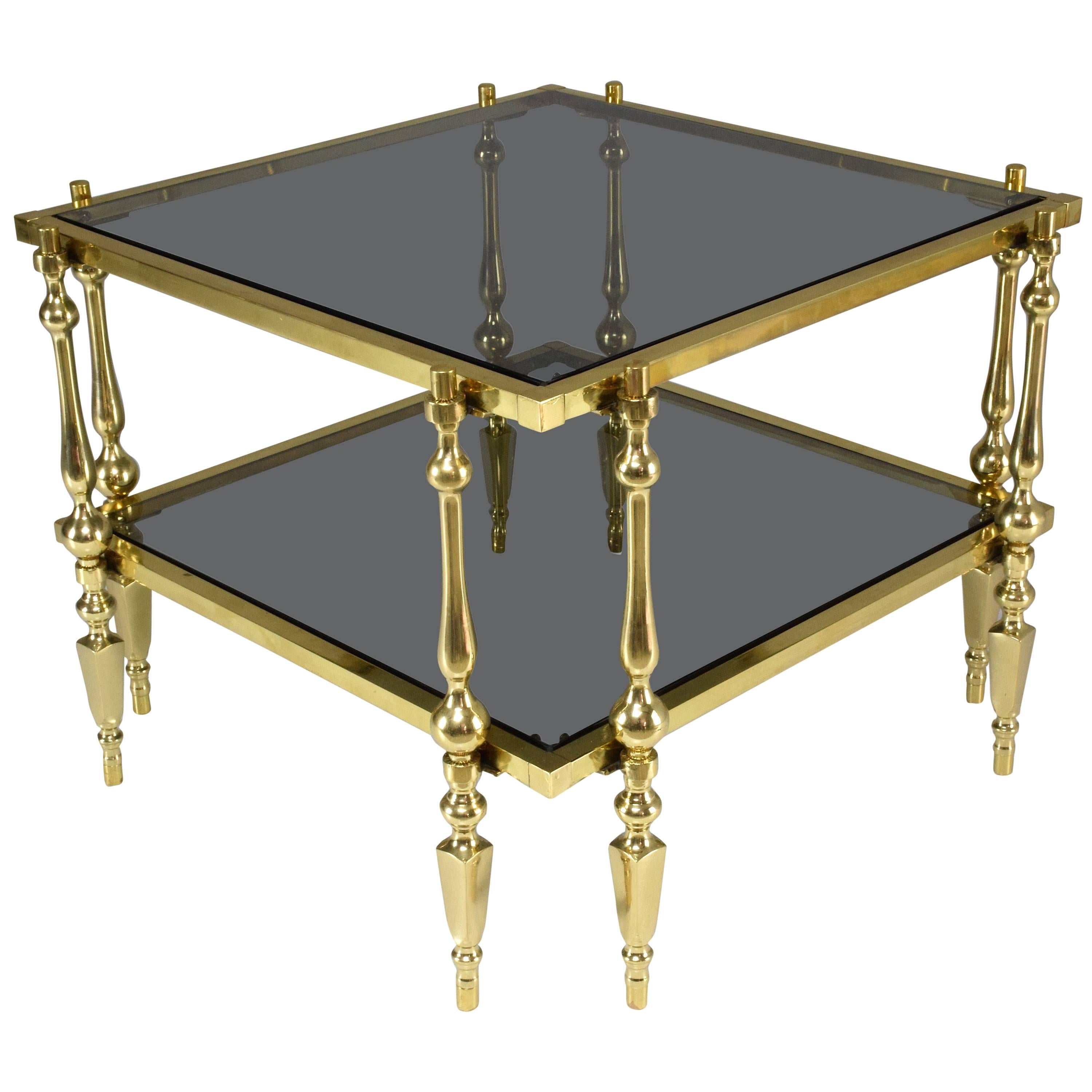 A French late 20th century vintage square two-tiered coffee or side table designed with a solid polished gold brass structure, smoked glass and intricate double sided fluted legs with spherical designs all-over.
In restored condition with original