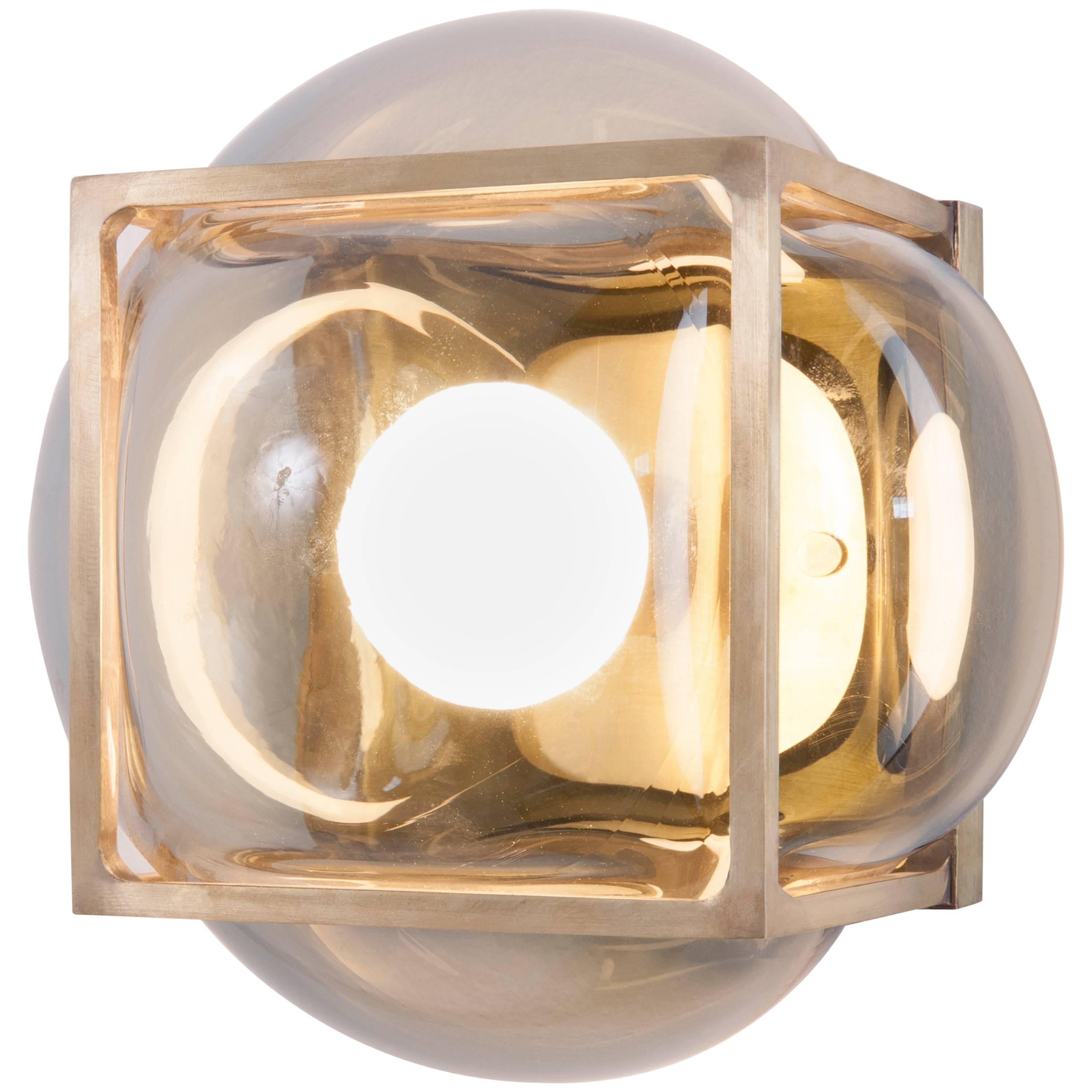 The Bulle can be used as a flushmount, a sconce or a tabletop fixture. The glass is hand blown into the solid brass frame. The hand blowed glass is available in either clear grey or opal white. Finish options for the metal frame are either blackened