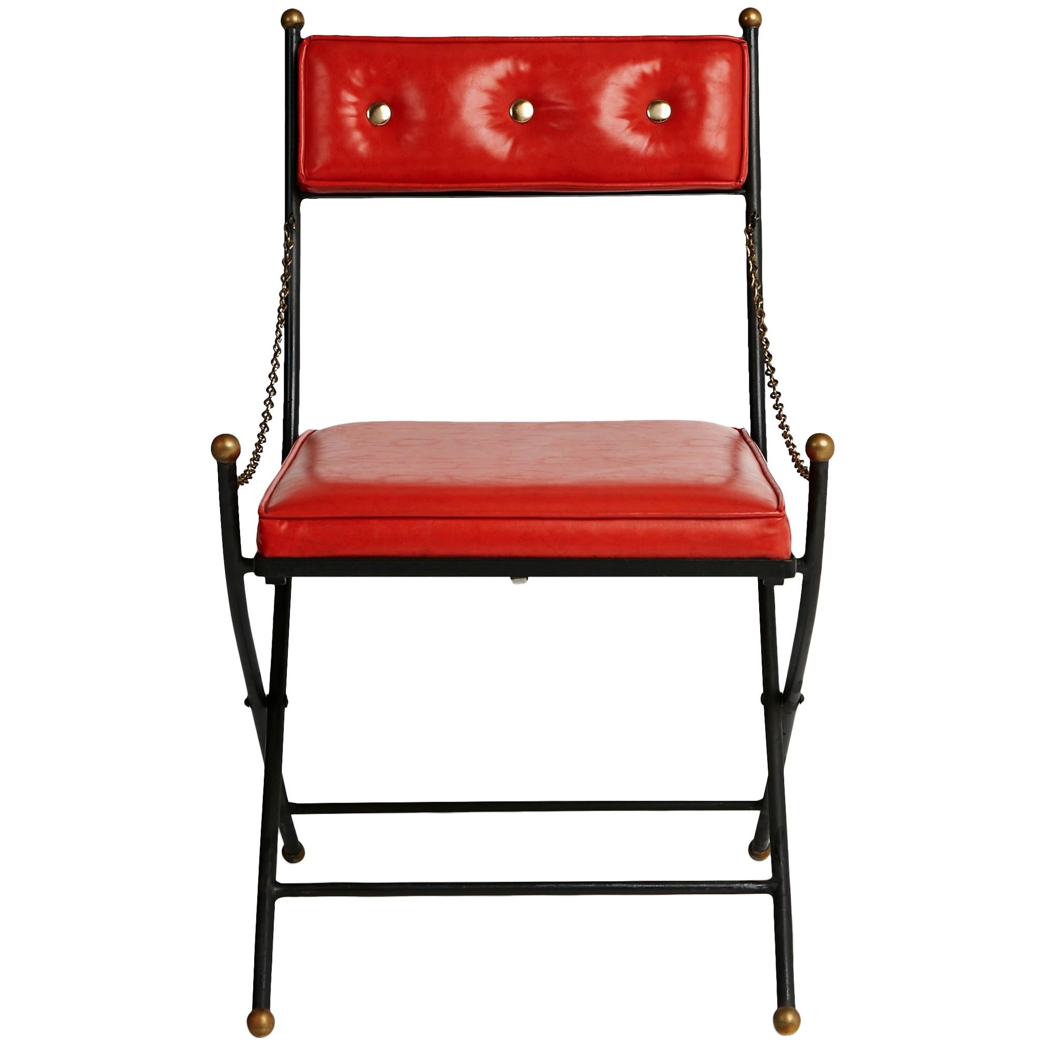 Set of four (4) campaign folding chairs in the style of Maison Jansen and Tommi Parzinger. This elegant Mid-Century Modern meets Hollywood Regency set comprises of four red folding chairs upholstered in faux leather. They feature brass metal