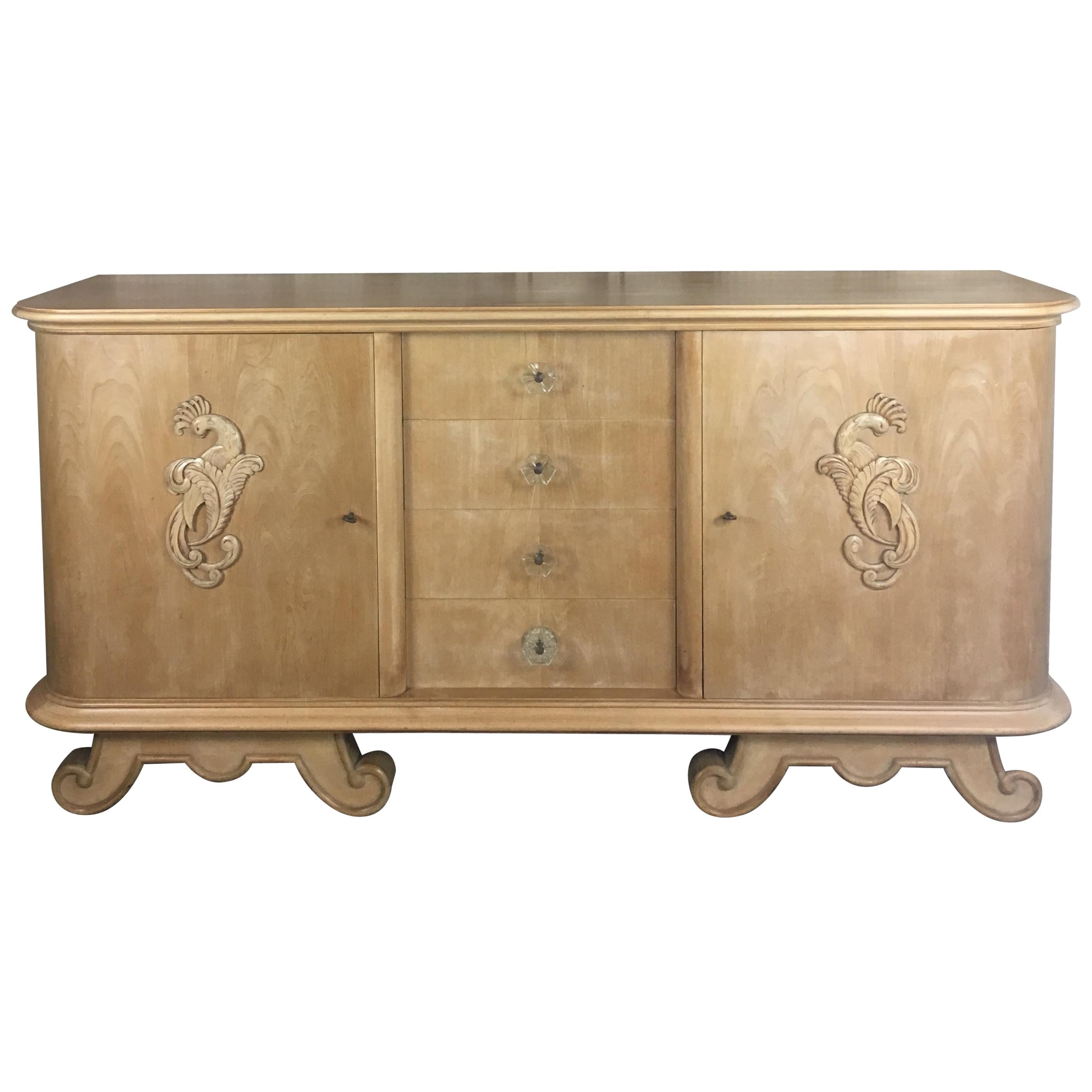 A stunning French midcentury sycamore credenza or buffet in the style of Andre Arbus with 4 drawers behind two doors having centered hand carved phoenix and trim above scrolled feet, circa 1940s. 

Beautifully designed and well crafted with ample