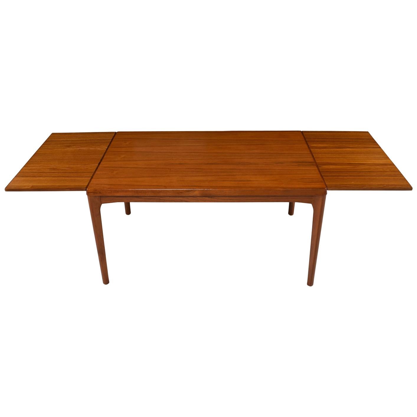 This large draw leaf Vejle stole dining table stands firm in its solid pine core covered with a teak veneer. Designed by Henning Kjaernulf for Vejle Stole og Møbelfabrik, this hefty beauty boasts solid teak legs and gorgeous edge banding. The