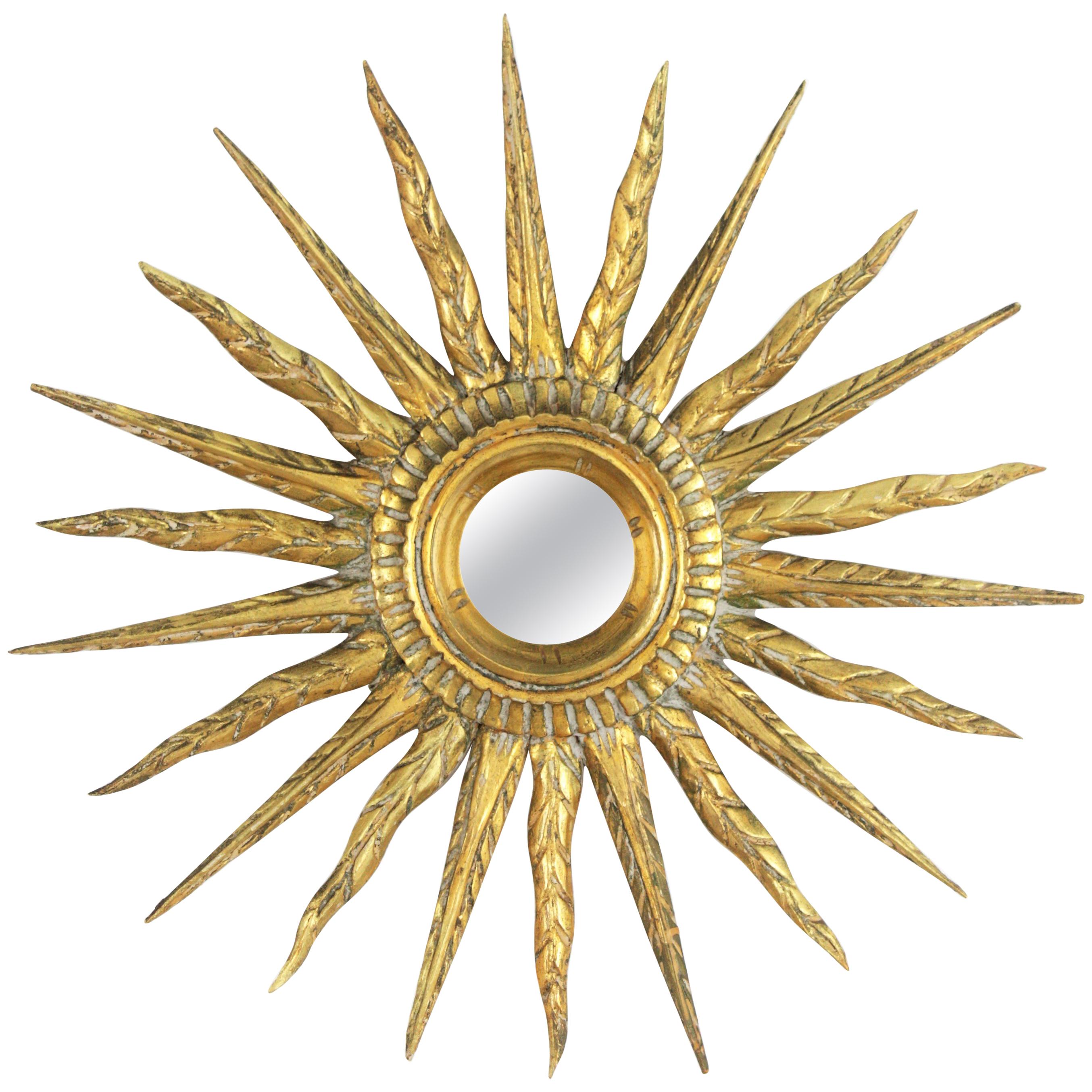 Sunburst Wall Mirror, Carved Wood, Gold Leaf, Spain 1930s-1940s.
Hand carved sunburst mirror with gold leaf gilding.
A very beautiful small sunburst mirror finely carved with 24 k gold leaf finish and green accents. 
Very unusual size and