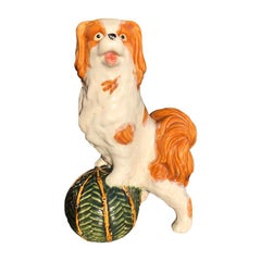 Statue en céramique représentant un chien vert avec un boulet, dans le style du Staffordshire