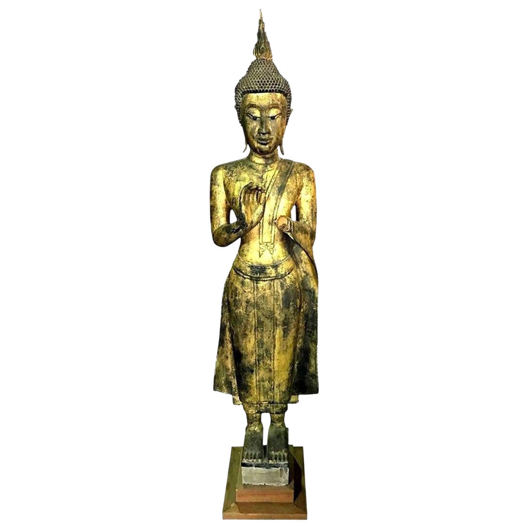 Grand Bouddha asiatique en bois sculpté et doré, debout, dans un temple serein
