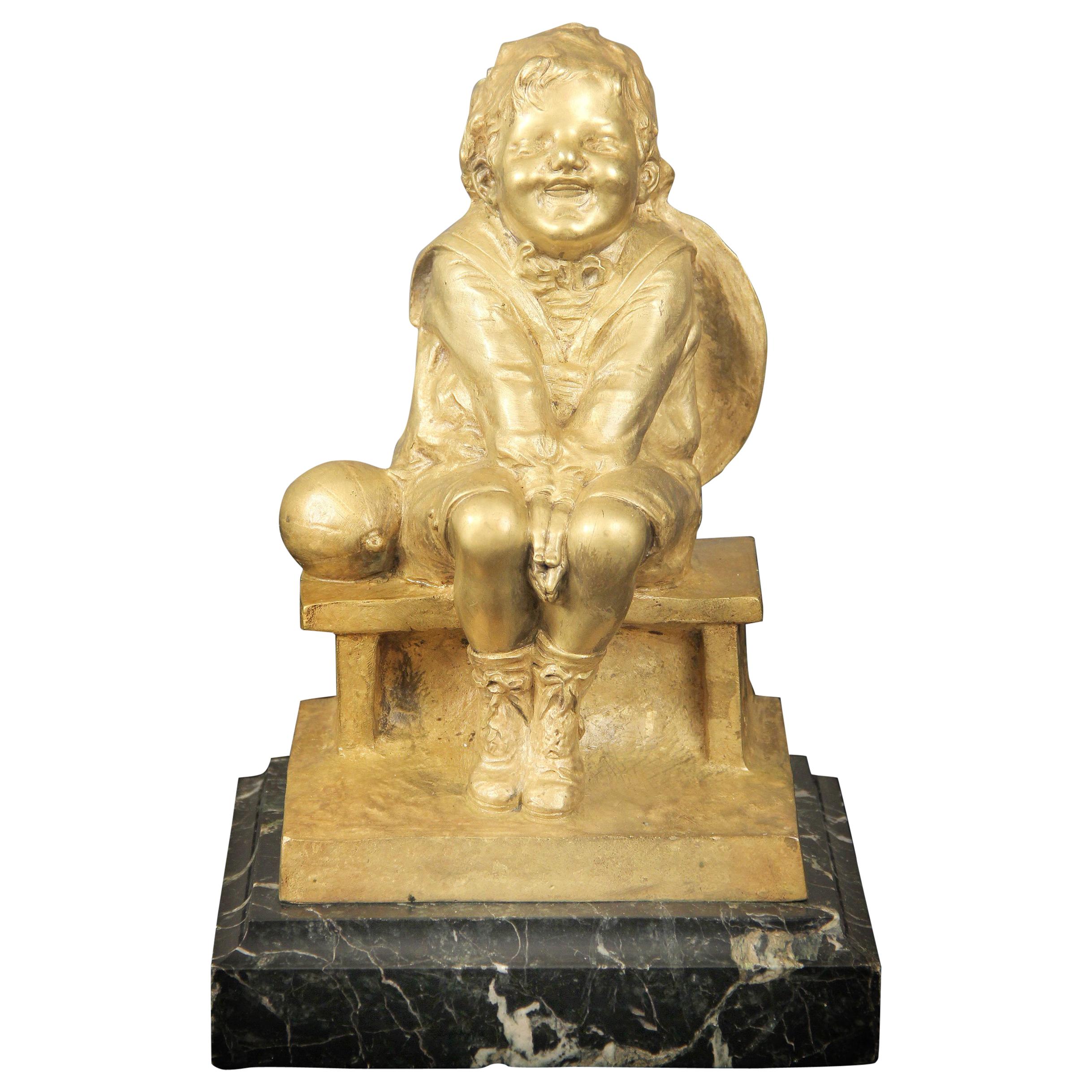 Belle sculpture en bronze doré d’un enfant assis sur un socle en marbre par Juan Clara