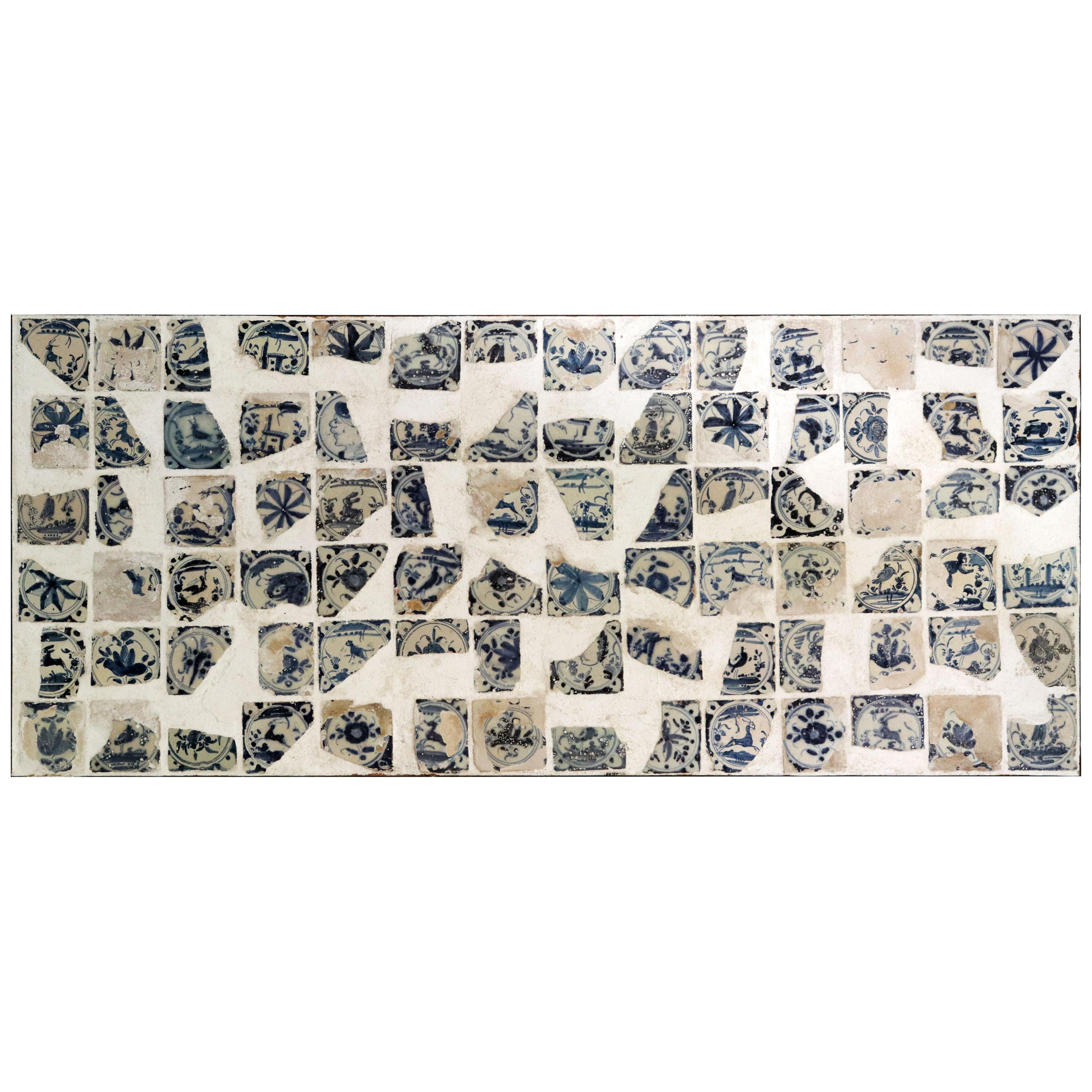 Fragments de céramique émaillée du XVIIIe siècle disposés sur un panneau encadré de fer