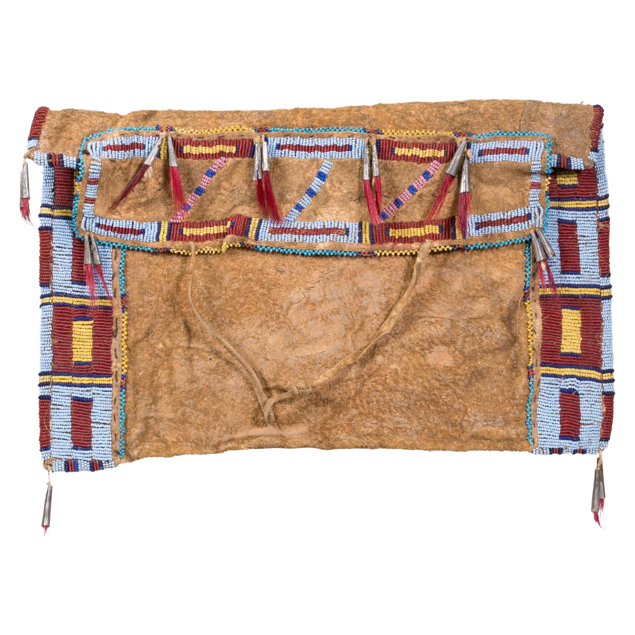 Hidatsa Sioux work bag from Fort Berthold, North Dakota. Properly referred to as a woman's work bag that was used for holding sewing materials, sinew, awls and beads. Sinew sewn on brain tanned buffalo calf skin. Tin cones with horse hair tassels.