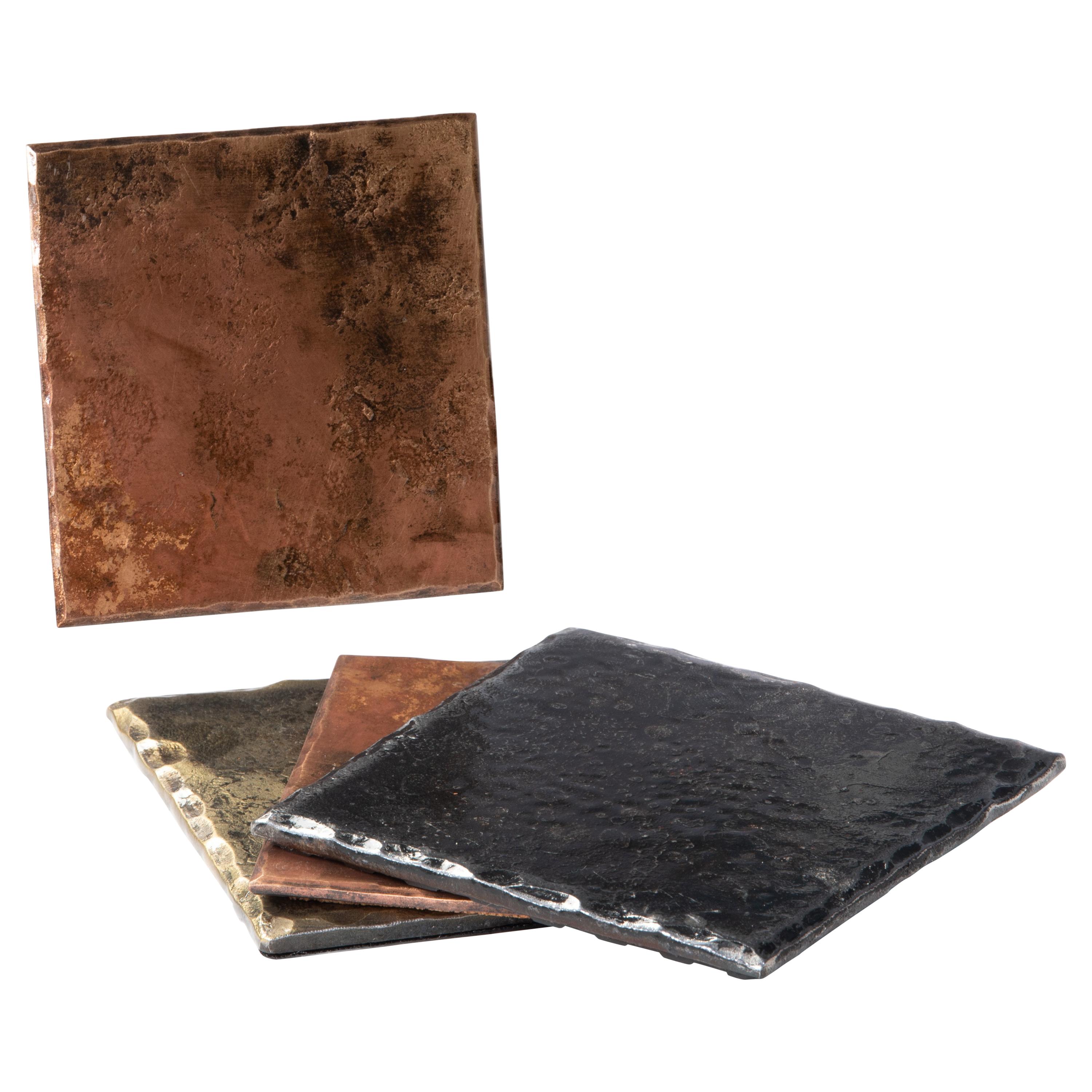A handcrafted, square coaster made from bronze that has been forge textured over a rough steel anvil face to provide texture. The edges are hammered and beveled. The bronze is burnished to accentuate the rustic, forged details. The oxidized, brushed