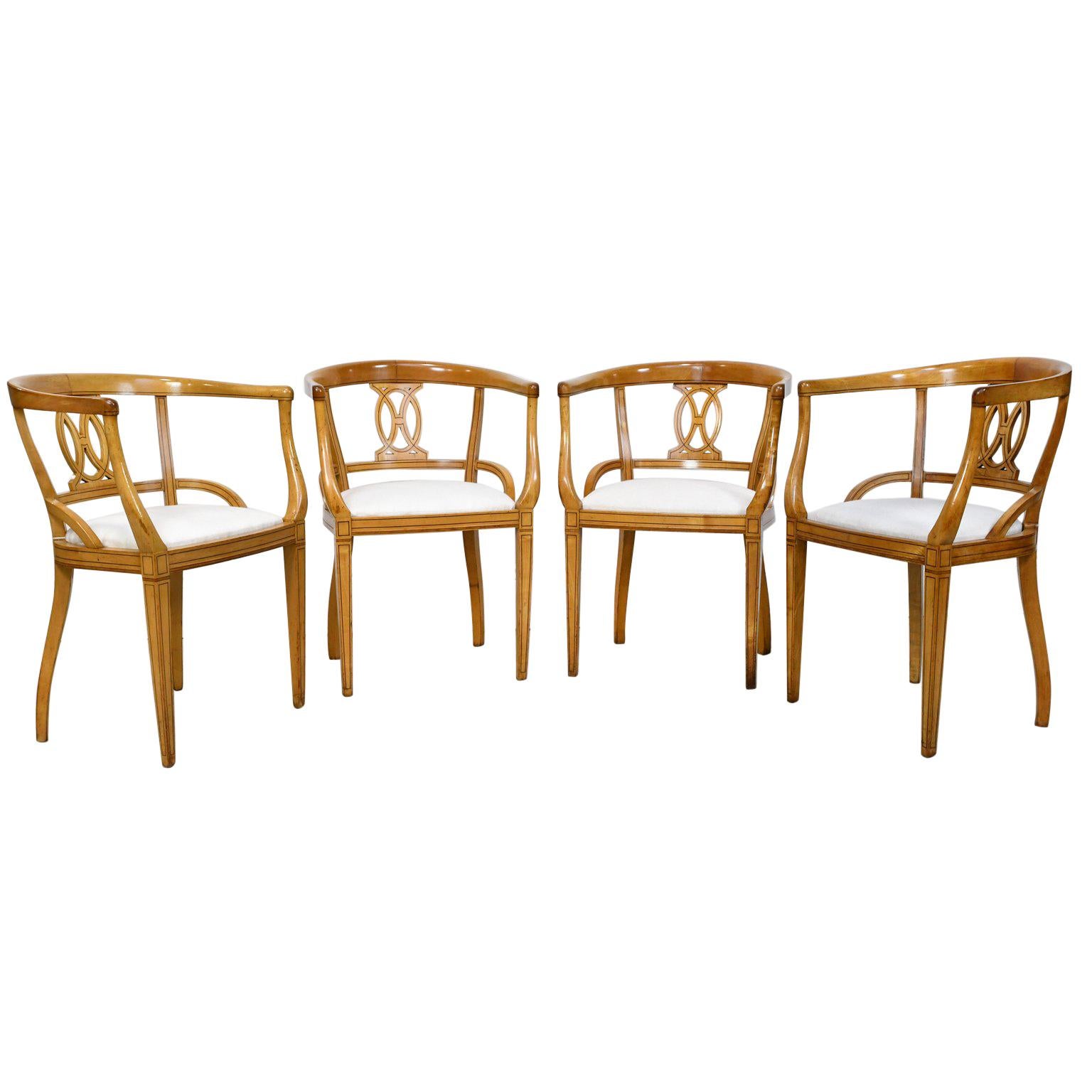 A set of four very handsome Scandinavian Biedermeier armchairs in blond birchwood with barrel-back and tapered legs, circa 1830. Chairs feature ebonized wood, line inlays that accentuates the geometrical pattern on the carved back-splat and
