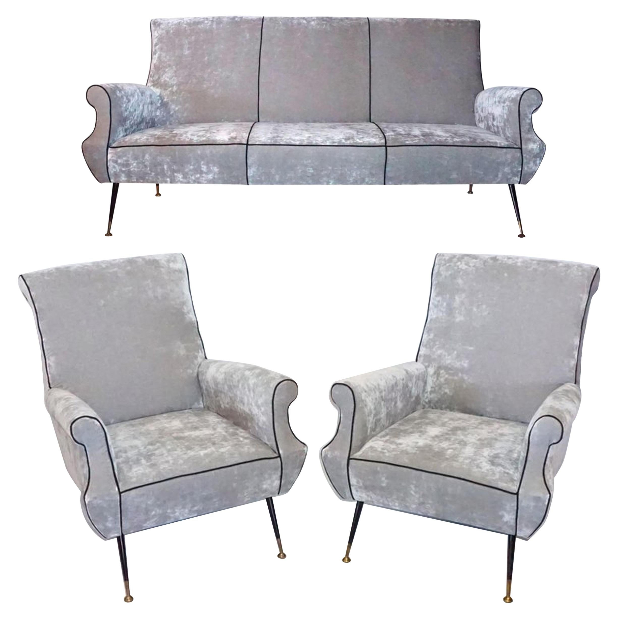 A vintage Mid-Century Modern Italian silver seating ensemble designed by Gigi Radice and produced by Minotti. Two lounge chairs and one three-seat sofa on conical iron legs with brass sabots which have been reupholstered with a high quality silver