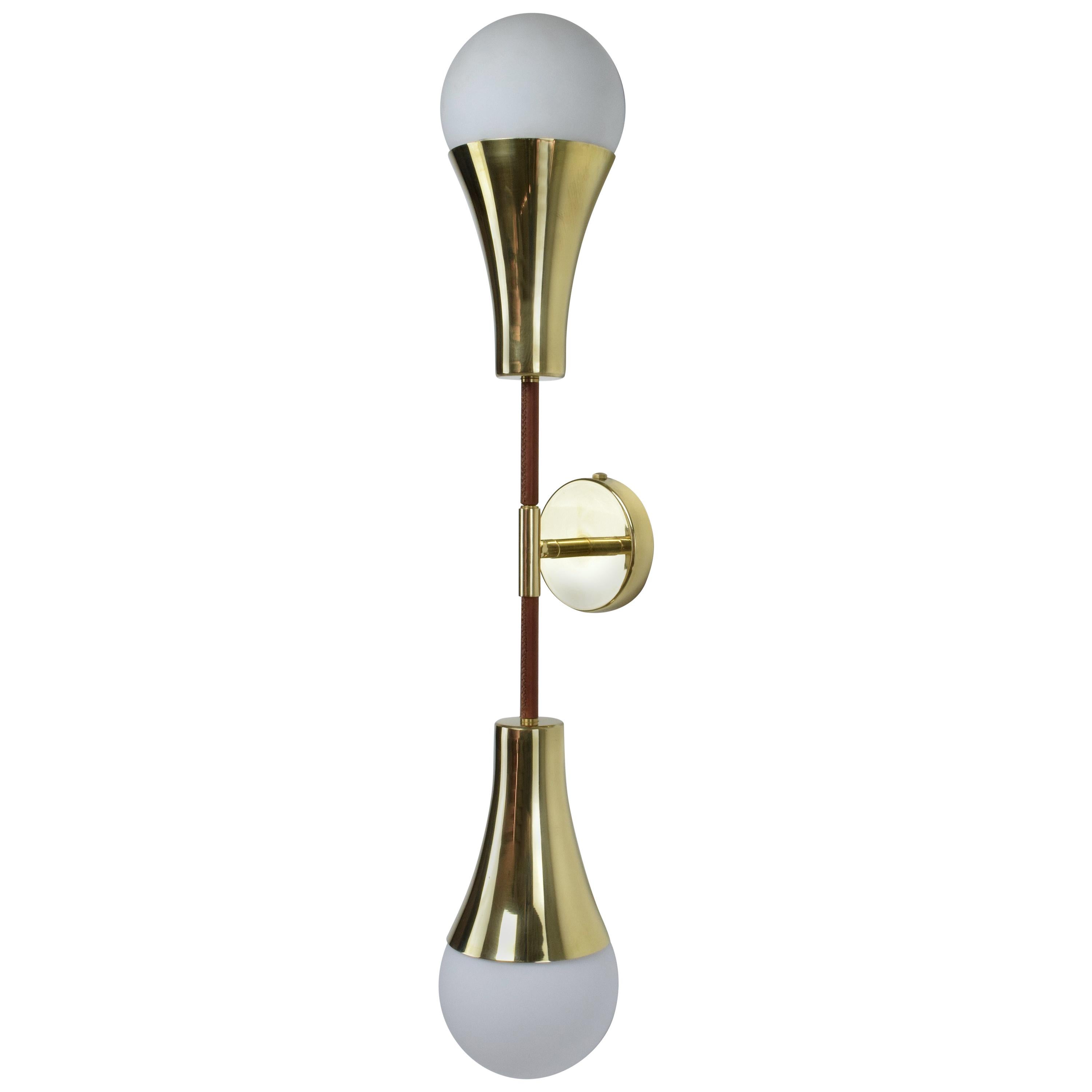 Contemporary modern handcrafted wall lamp fixture or sconce, composed of a double gold polished solid brass and opaque glass boule light shades and designed with a leather sheathed detail on both ends of the stems hand sewn by artisan saddlers. 
