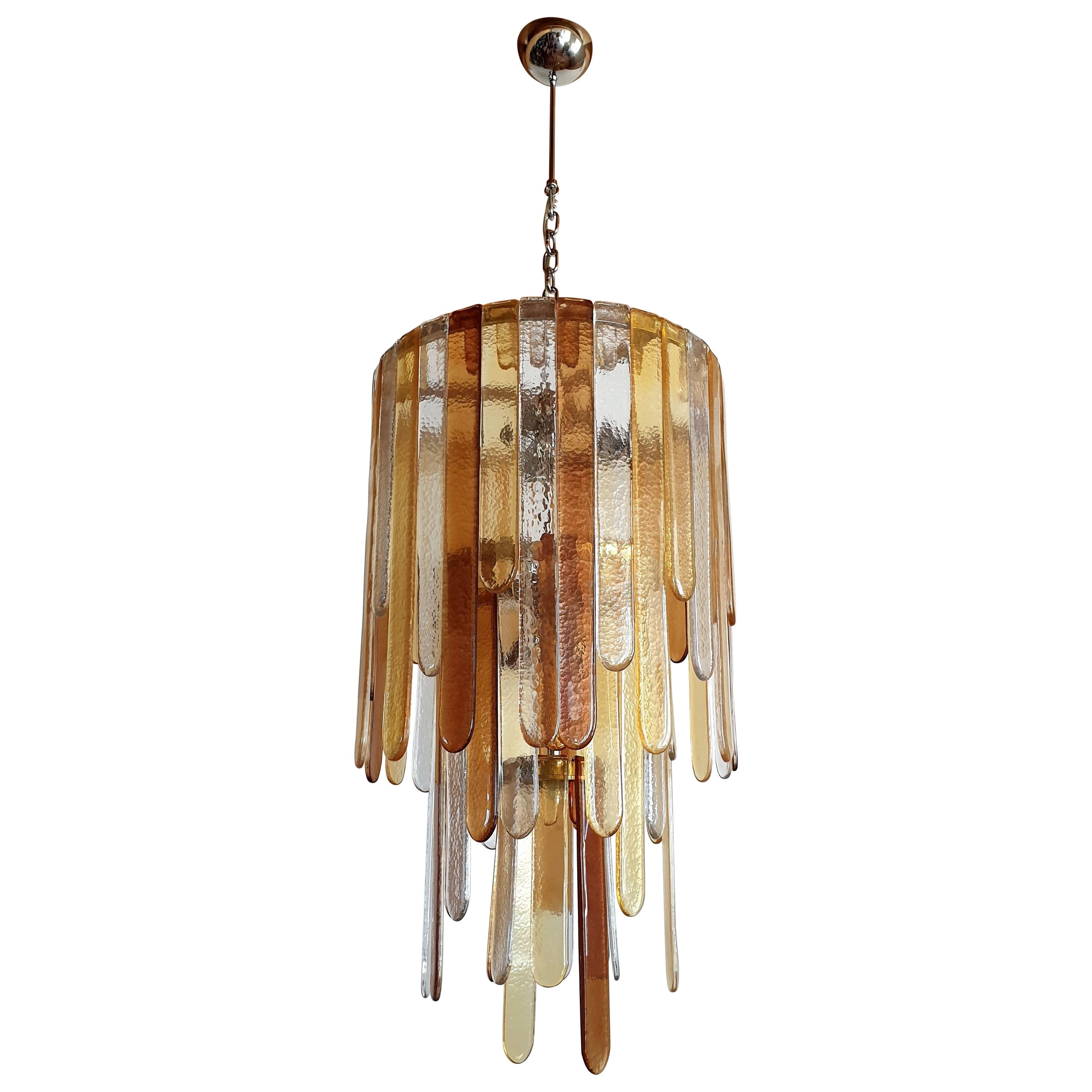 Large Mid-Century Modern Murano glass pendant chandelier, by Mazzega, Italy, 1970s.
With 3 tiers of Murano glass hooks: transparent, honey and light brown; in 4 different heights, giving a rythm, a cascading effect.
6 lights, rewired for medium