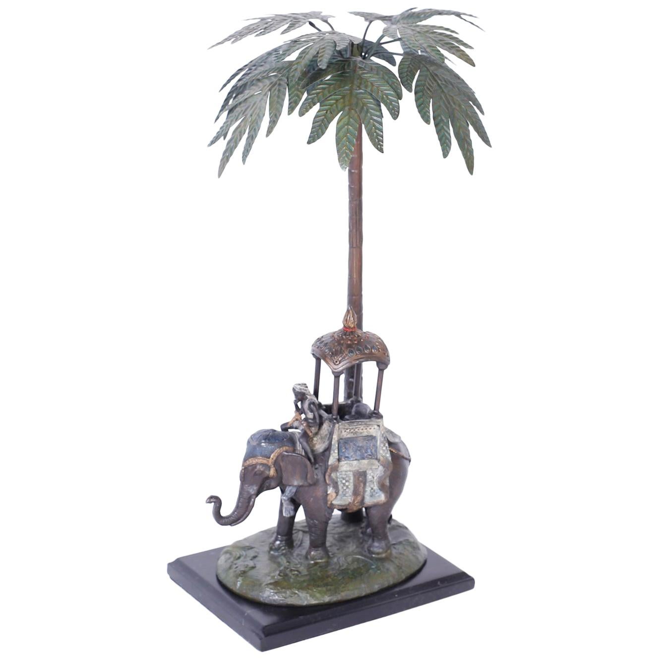 Kalt bemalte Metallfigur eines Elefanten unter einem Palmenbaum
