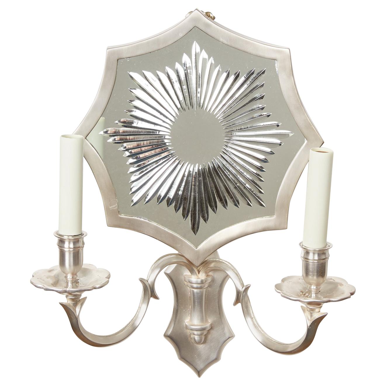 A pair of custom silver plated bronze sconces featuring an octagonal mirrored backplate with wheel cut design. The mirrored sunburst sconce issues two arms and two candelabra sockets per fixture.