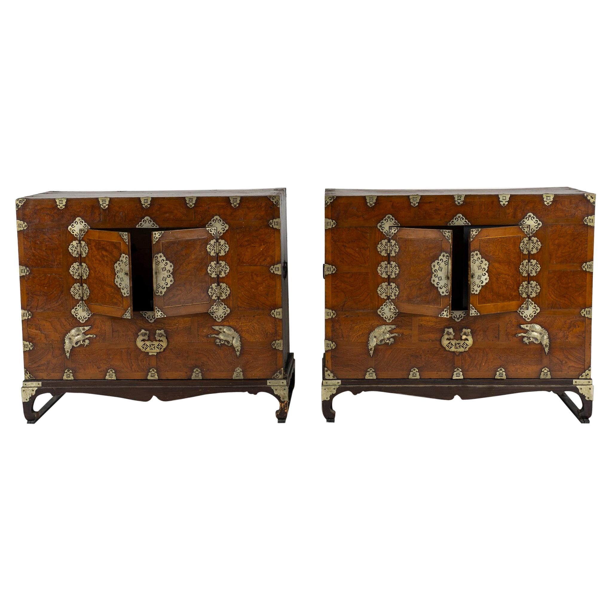 Pair of 19th century Korean side chests with small double doors and traditional cut brass hardware. Hidden sliding interior panels and small storage boxes within. Cabinets each sit atop hand carved bases that are not attached. Two chests can be