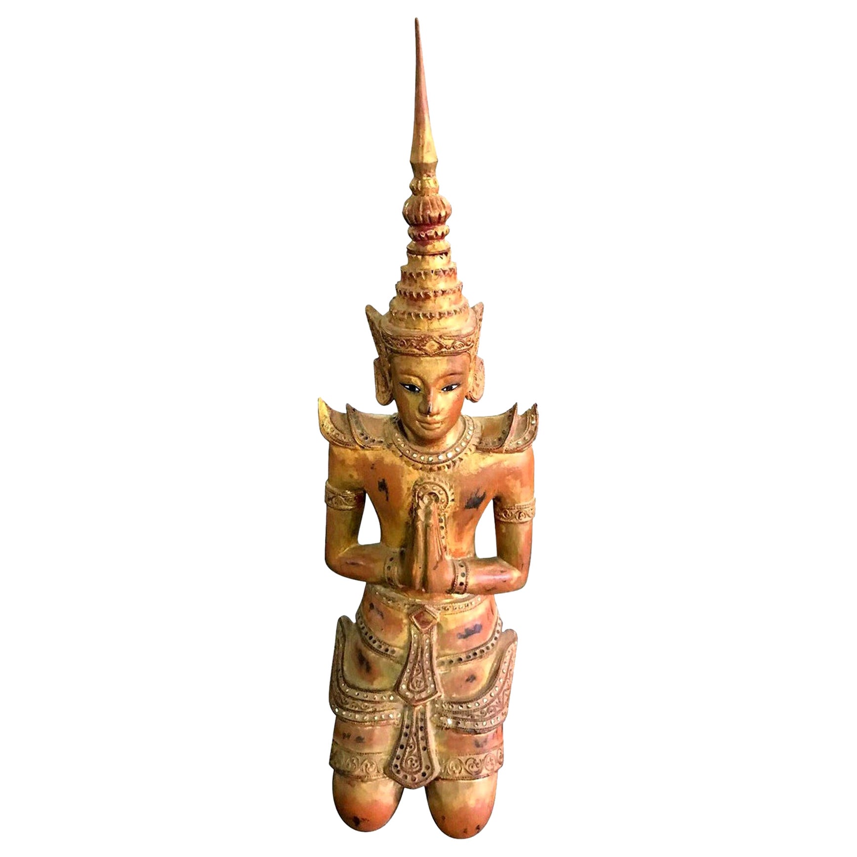 Grande figura asiatica tailandese in legno intagliato, laccata e dorata, inginocchiata nel tempio del santuario in preghiera