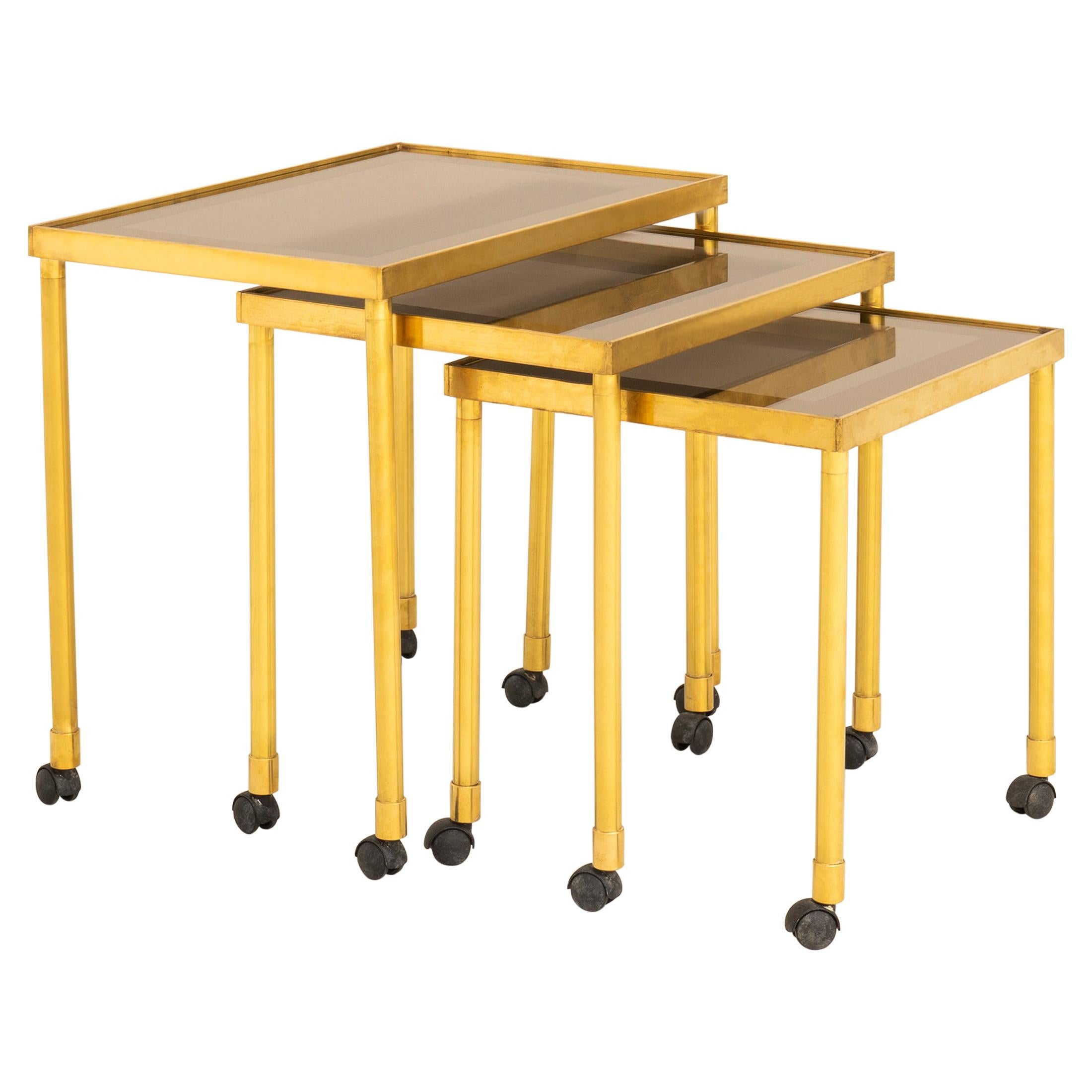 Italian 1970s nest of brass tables on wheels with smokey glass tops For Sale