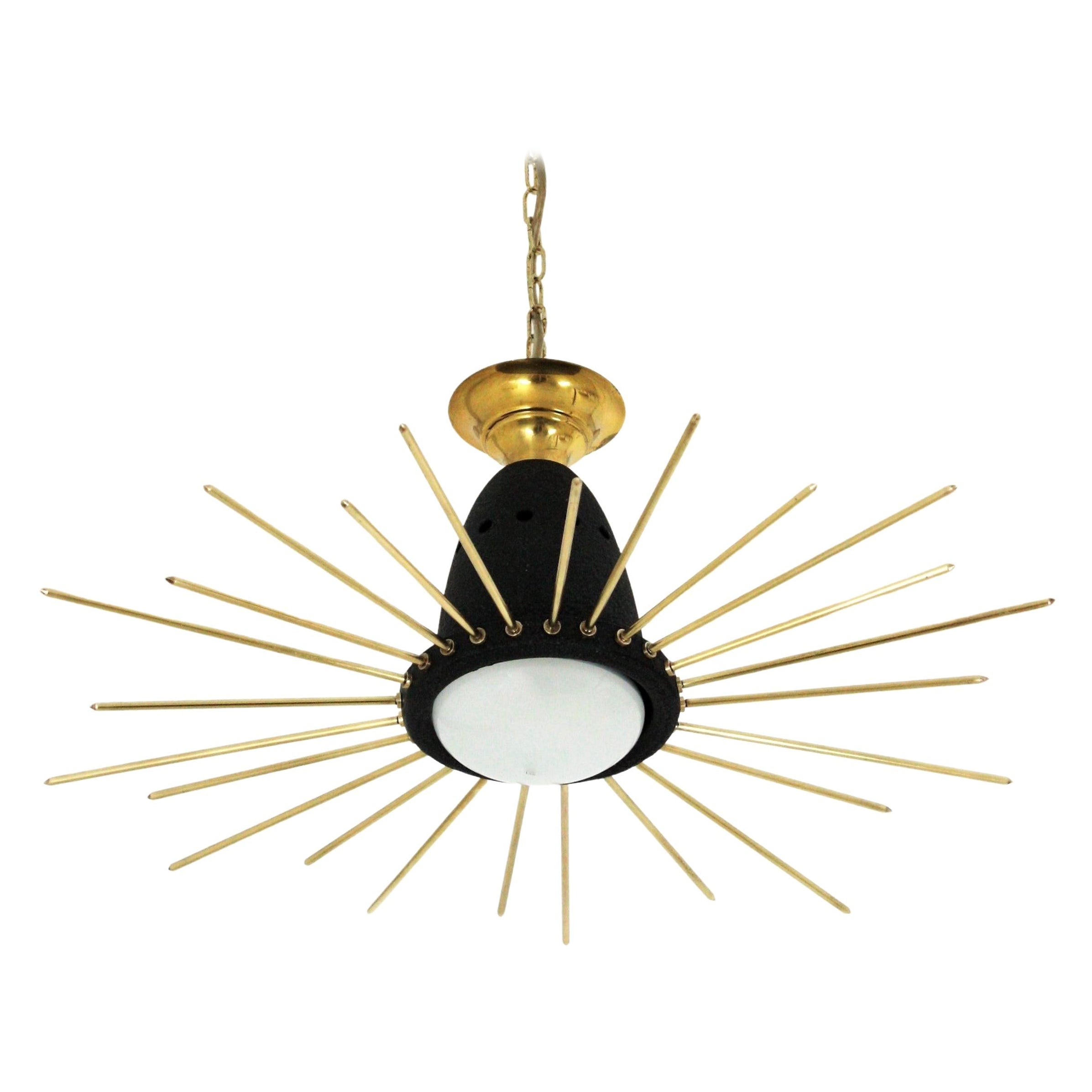 Mid-Century Modern black lacquered metal and brass sunburst suspension light or light fixture, Italy, 1950s.
This eye-catching ceiling lamp features a black lacquered metal shade topped with a brass canopy and surrounded by brass rays in two sizes.