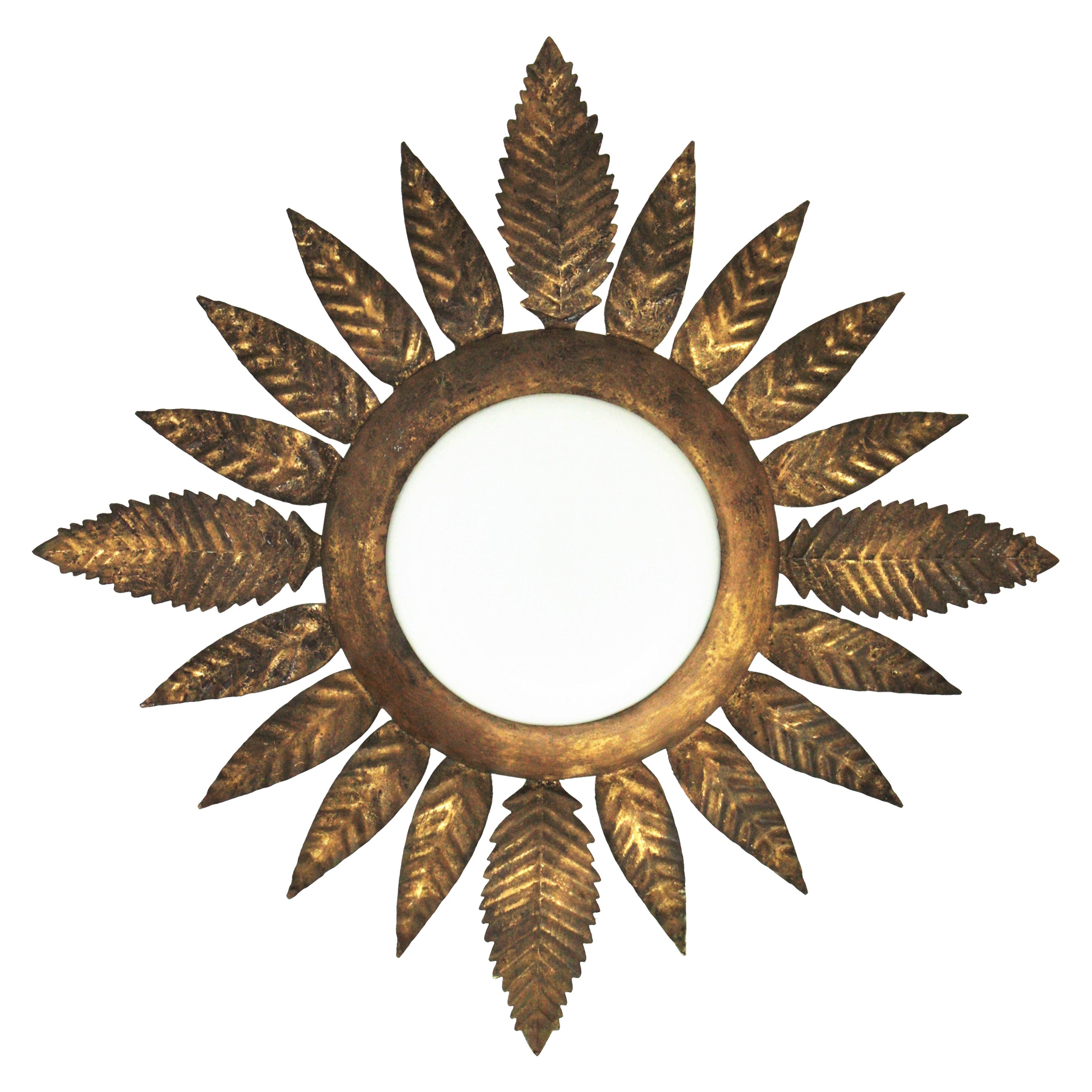 A nice gilt iron flower / sunburst flush mount with leafed frame. France, 1950s
This light fixture features an opaline glass circular shade surrounded by a frame of hand-hammered iron leaves with gold leaf finishing.
It can work as ceiling light