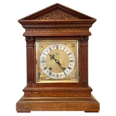 Horloge de cheminée ancienne à huit jours en chêne sculpté avec visage en laiton