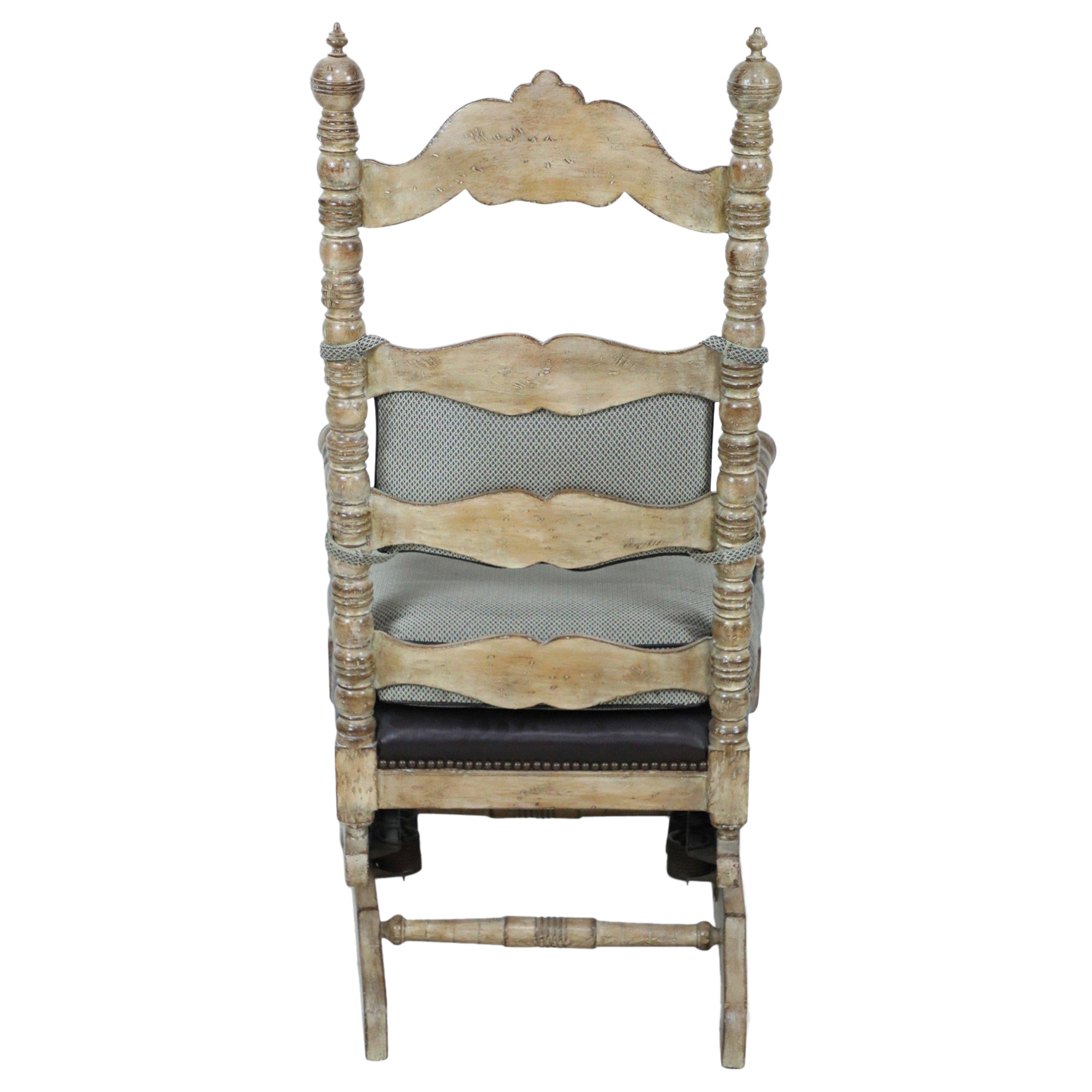 American Victorian-style platform rocking chair with upholstered gray fabric seat and back cushion with a carved back rail and turned spindle arms and legs. The base cushion is a dark leather finished with decorative furniture tacks.
  