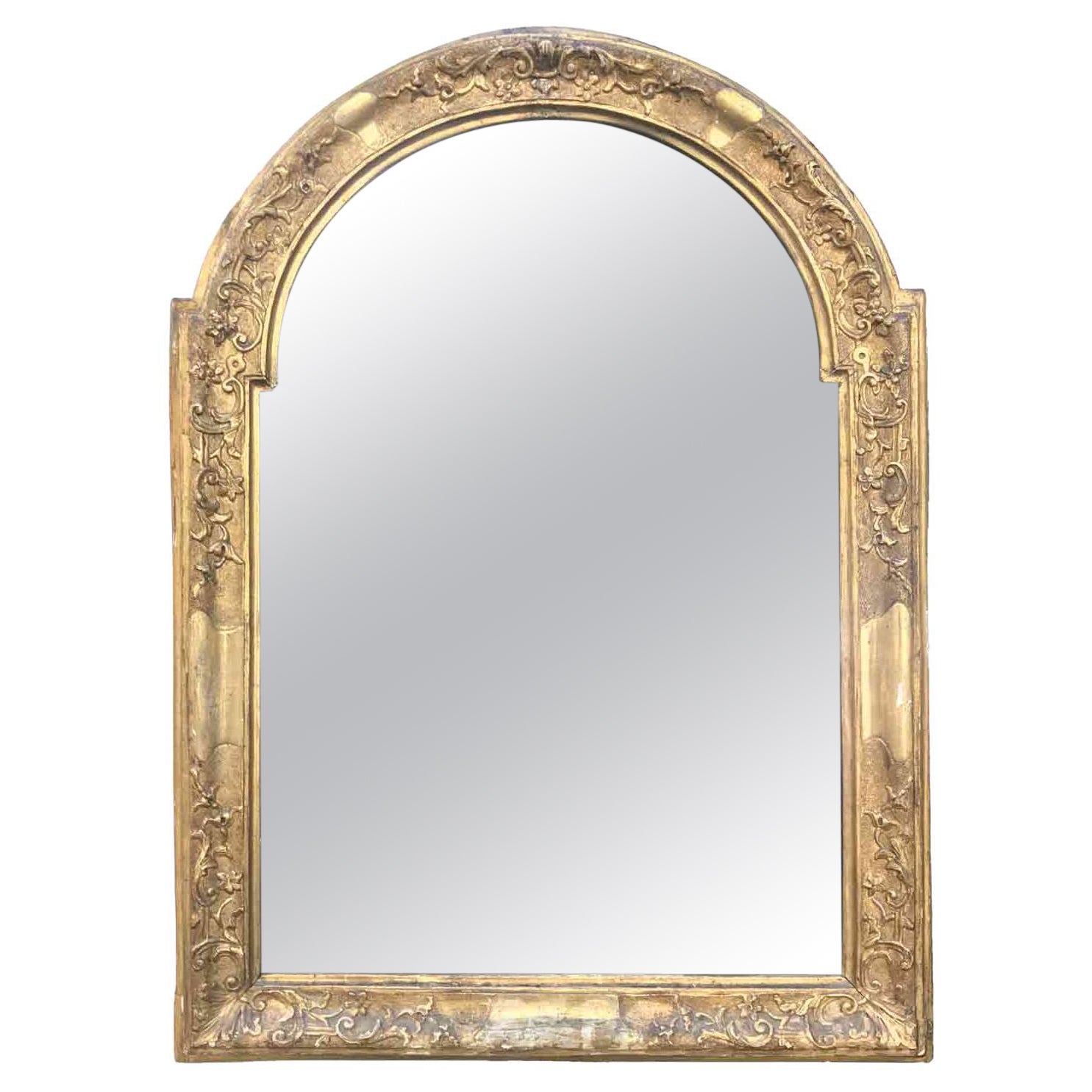 Napoleon III carved and golden leaf gilded wooden mirror with antique original mercury glass dating back to late 19th century, of French origin.
This arched-shaped centinata French frame is hand-carved with bulino, creating a punched ground finely