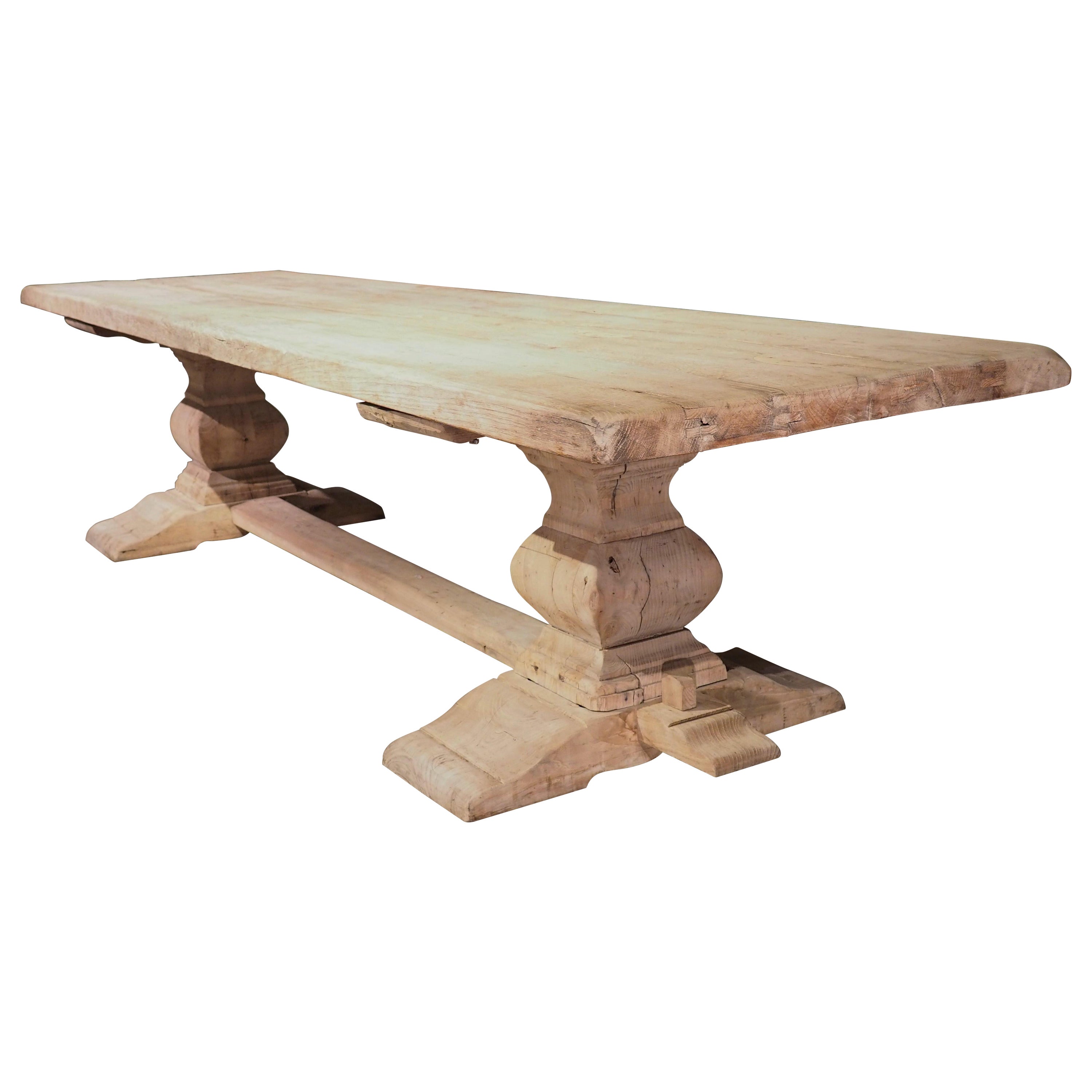 This thick, carved oak monastery table was produced in France, circa 1890. Originally built using large pieces of French oak, and given a darker, more traditional stain. At some point in its history, the table was stripped and bleached, allowing it