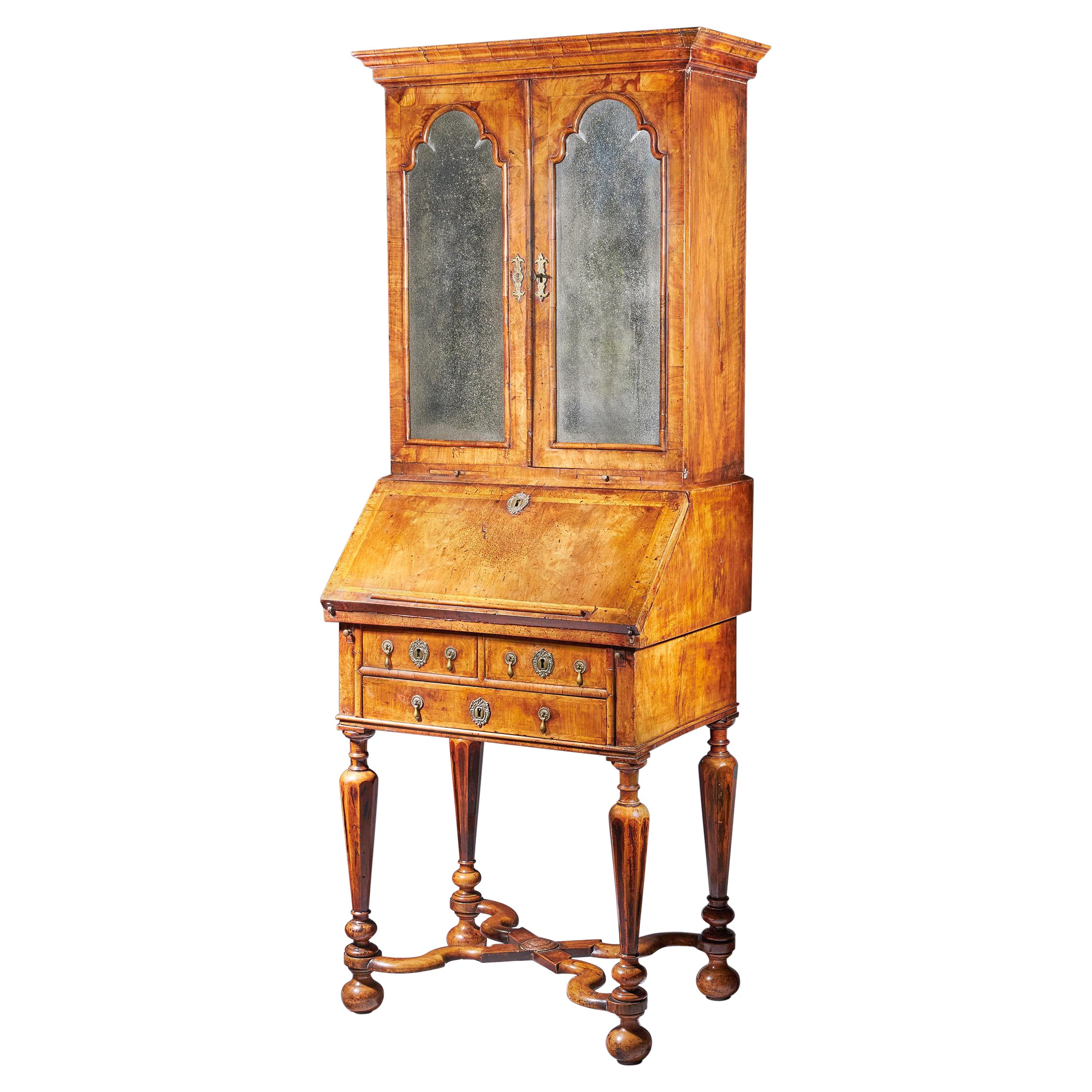 An exceptionally rare William and Mary period walnut writing bureau and bookcase on stand of diminutive small proportions, C. 1695 England. 

The ogee cross-grain moulded cornice above a pair of hinged doors with shaped softly bevelled mirror