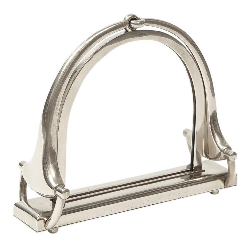 Gucci Horsebit picture frame, nickel, signed. Stirrup form photo frame in polished nickel. The display opening is 5.63 inches in height by 5.75 inches wide. The four circular feet on the underside of the base unscrew, releasing the frame and