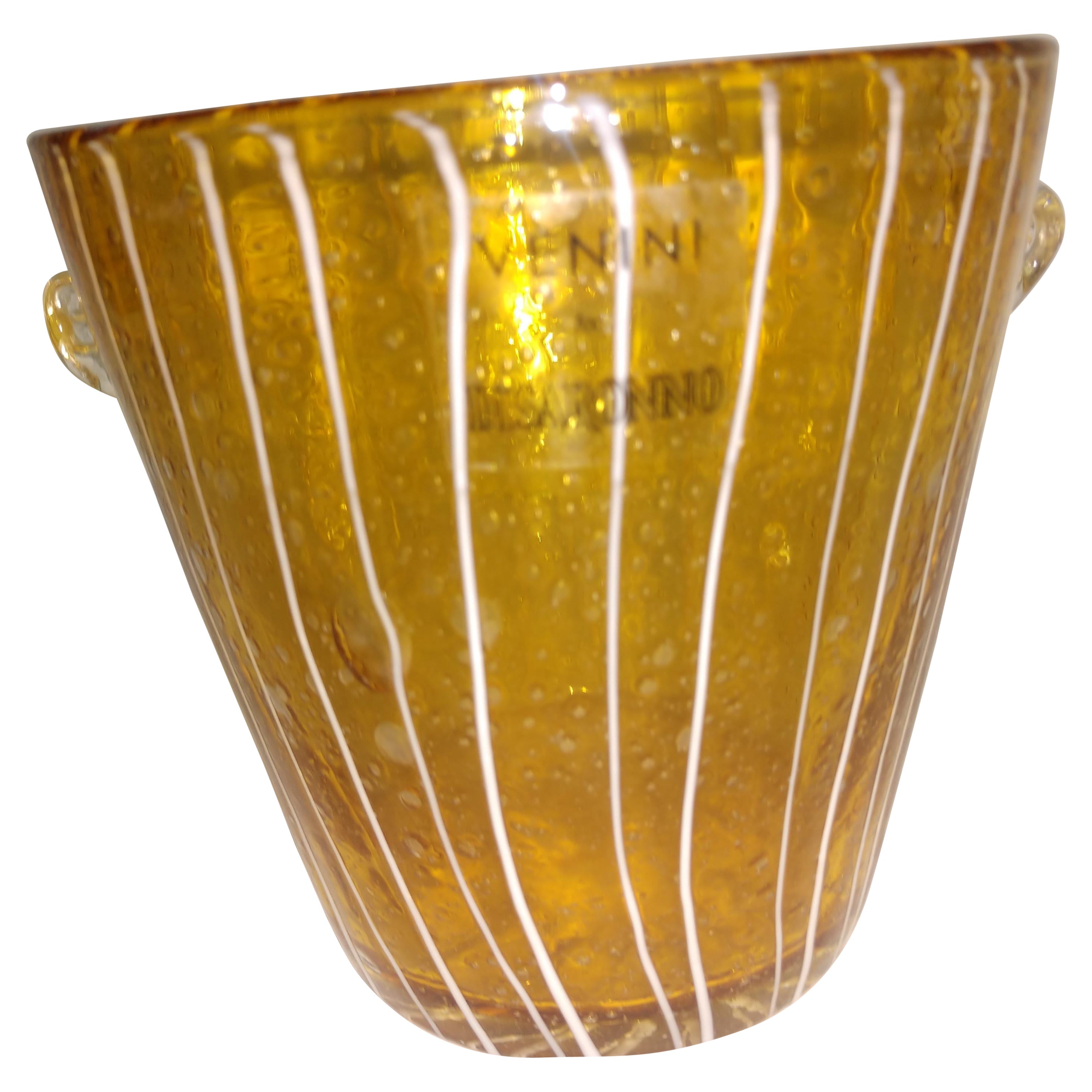 Un sorprendente vaso portaghiaccio in vetro artistico di Venini per Disaronno. Bellissimo bicchiere ambrato con una colatura a strisce bianche.
