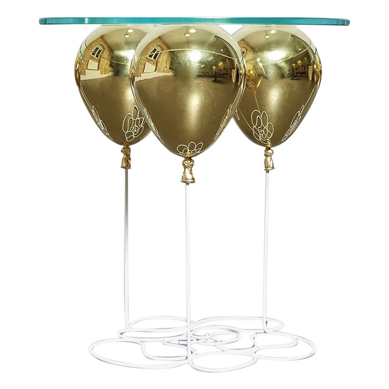 Small, circular side table with gold balloon and glass table-top.