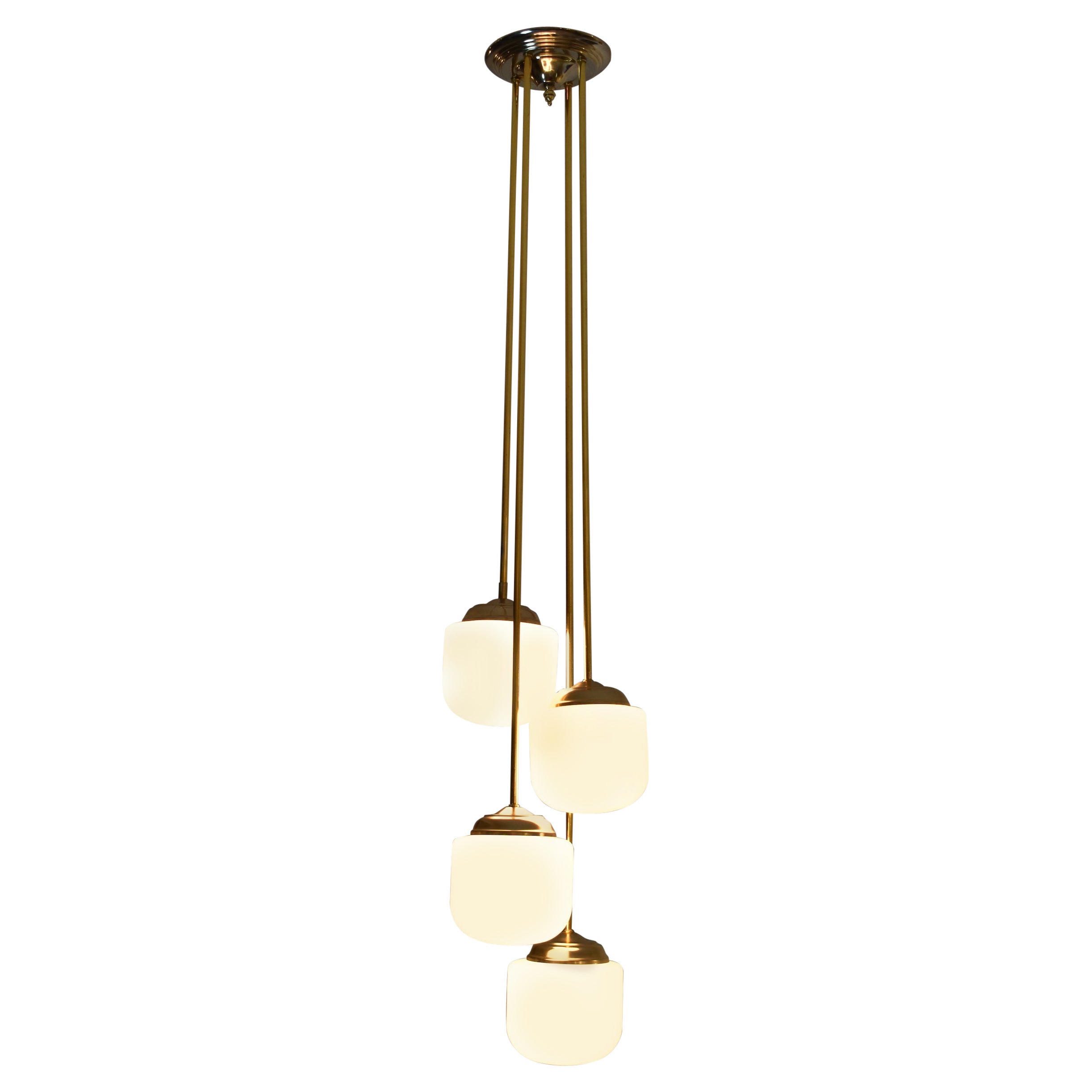 A chic Italian vintage pendant composed of four lights from the late 20th century. The beautiful organic-shaped opaline glass shades are highlighted by classic polished brass drops. 
The steel metal cover plate measures 20cm. 
All glasses are in