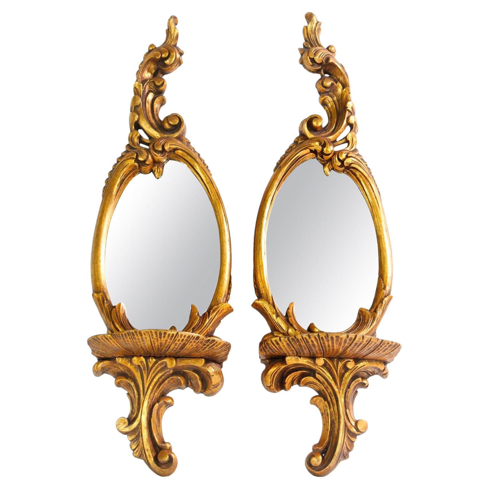 Paire de miroirs muraux en bois doré avec détails de feuillage et étagères en vente