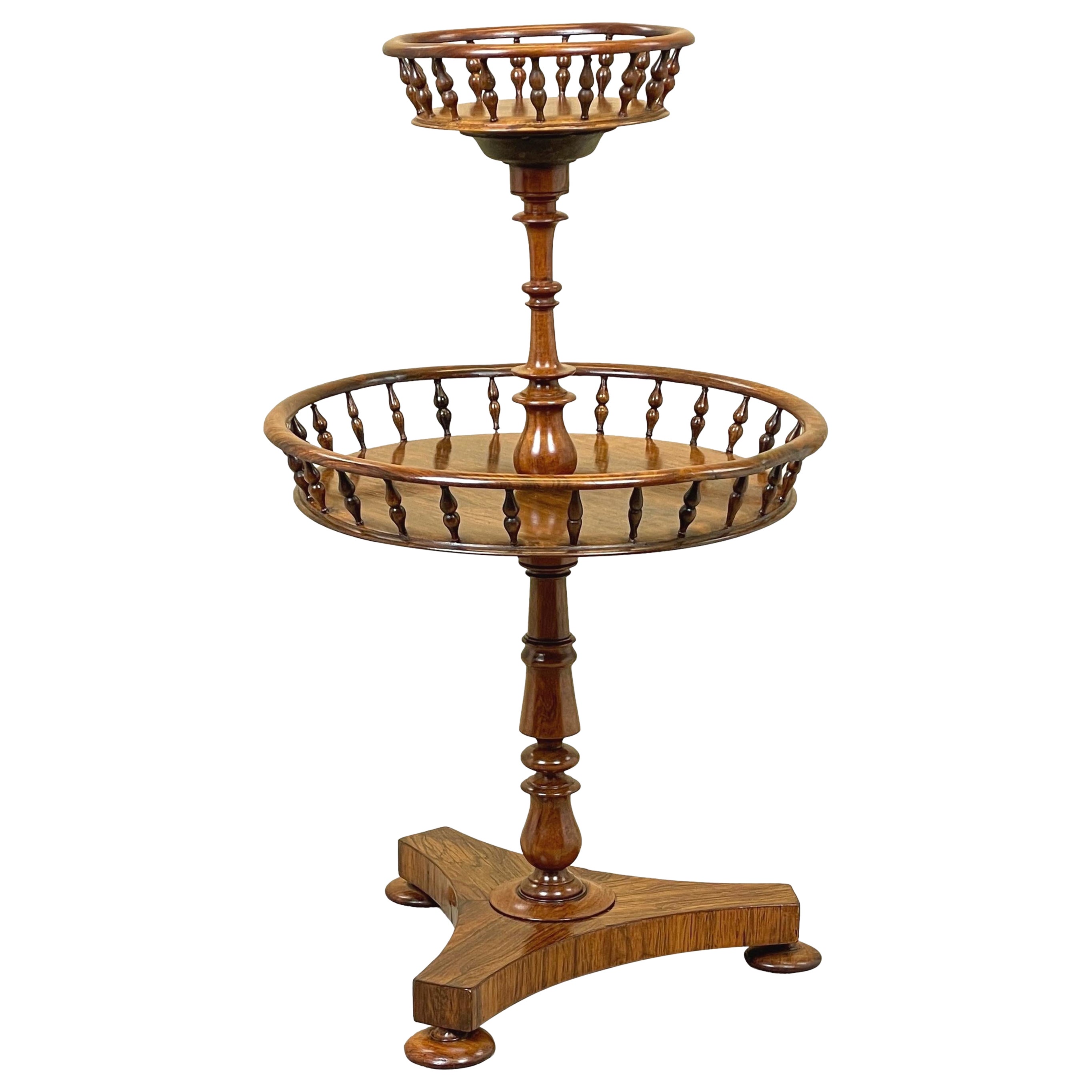 Mesa auxiliar circular de palisandro, de muy buena calidad y diseño inusual, posiblemente diseñada originalmente para guardar lana, con dos pisos circulares bien labrados y elegantes galerías torneadas, unidos por una columna central torneada que