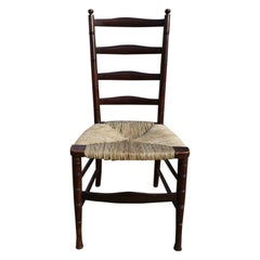 Liberty & Co. Chaise anglaise du mouvement esthétique, en noyer, à dossier en échelle et assise en jonc.