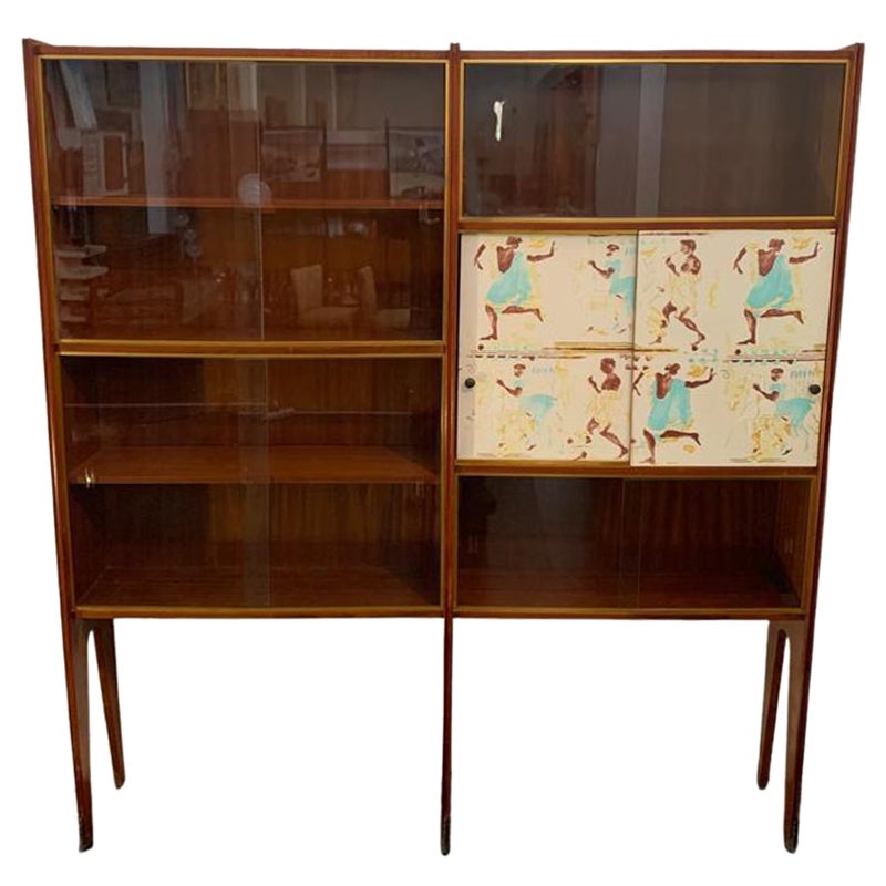 Vitrine Bücherregal (1 von 2) in blondem Mahagoni, 1950er Jahre
Dieses Möbelstück mit Bronzefüßen und Messingverzierungen verfügt über zwei Türen, die mit Dekorationen im Stil des griechischen Klassizismus geschmückt sind.
Der Stil, das Design und