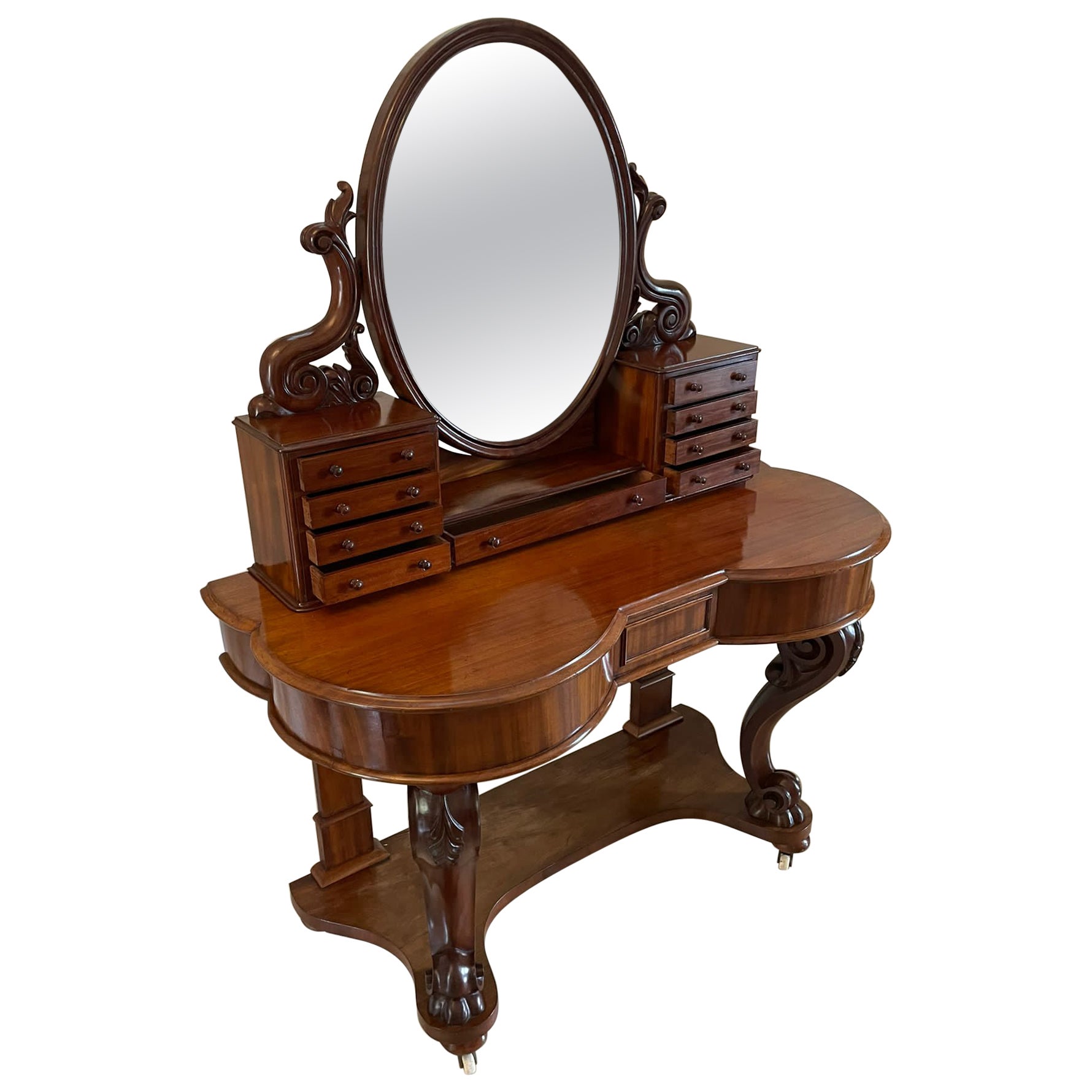 Antique Victorian quality mahogany dressing table having an oval shaped mirror in a mahogany frame supported by two shaped scroll supports above eight small and one long mahogany drawer with original turned mahogany knobs standing on a quality
