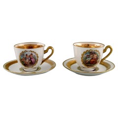 Two Royal Copenhagen coffee cups with saucers decorated with flowers.