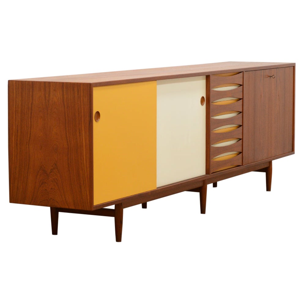 Early teak 29A sideboard by Arne Vodder for Sibast, Denmark 50s. Reversible sliding doors. Doors and drawers in teak, white and ocher and bar cabinet door has a black back. This sideboard can be used as room divider. The inside and back are also