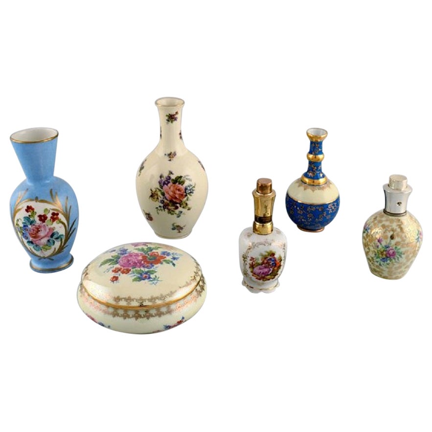 Limoges, France. Two perfume bottles, three vases and lidded box in porcelain.